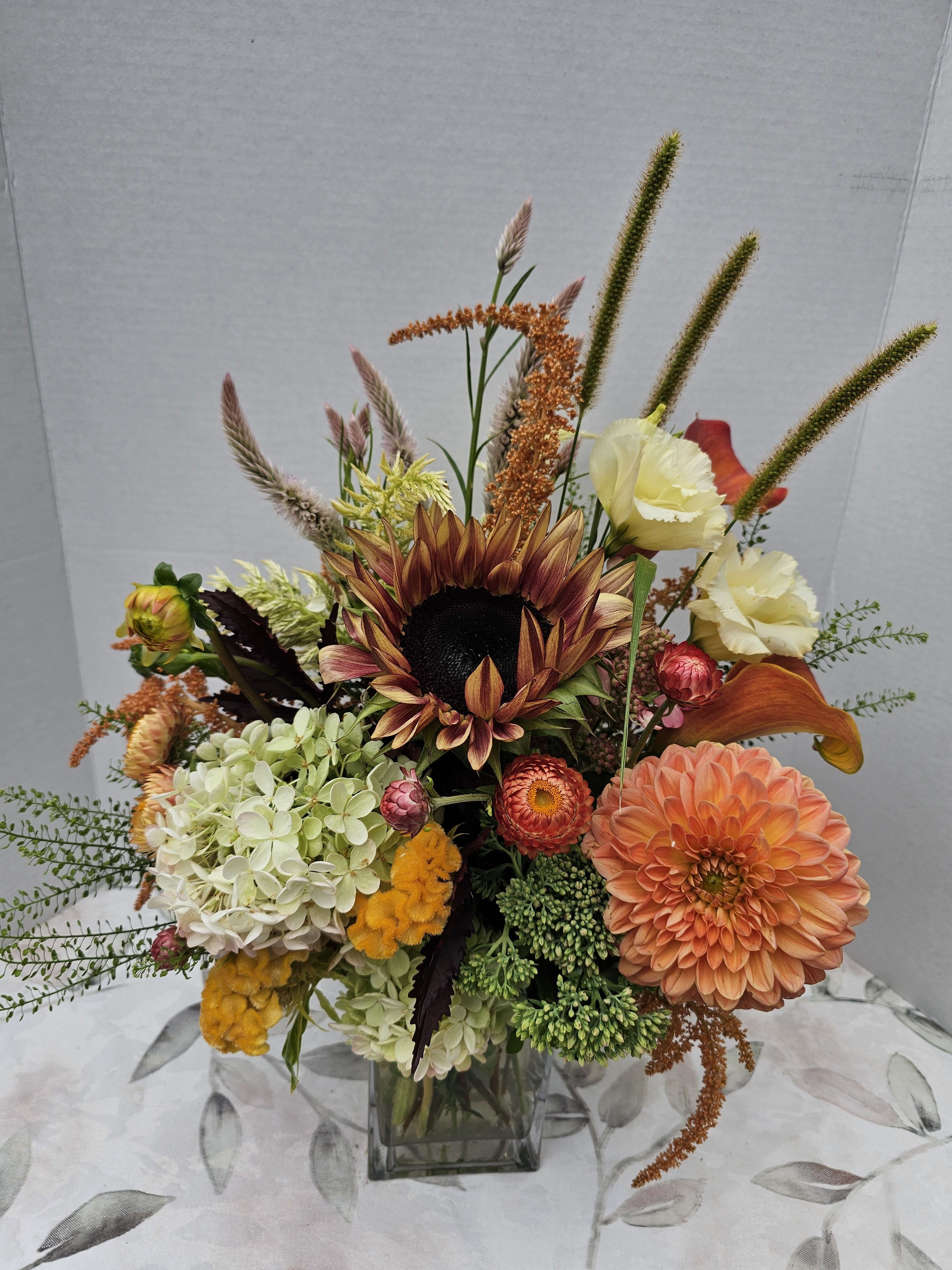 Calla fornia Sunset Calla fornia Sunset - calla lilys, sunflowers, hydragea and sunset colors arranged in a low square vase.