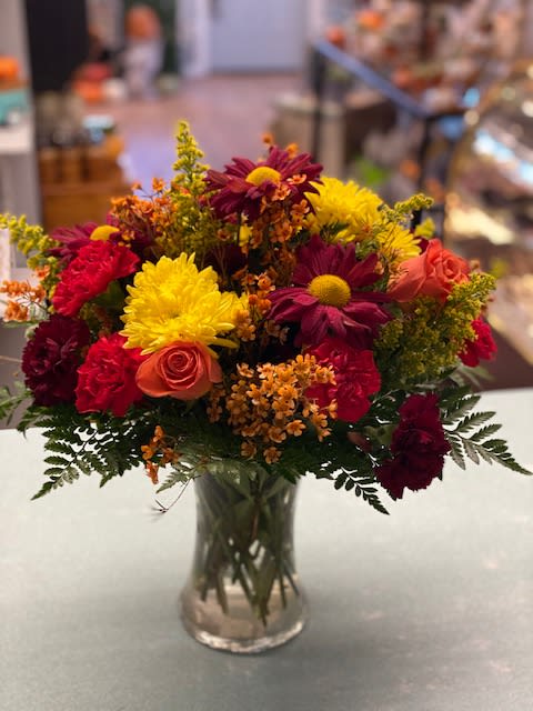 Fall Into Fall Fall Into Fall - Mums, carnations, rovermums, rose, solidago, wax flower in a gathering clear glass vase
