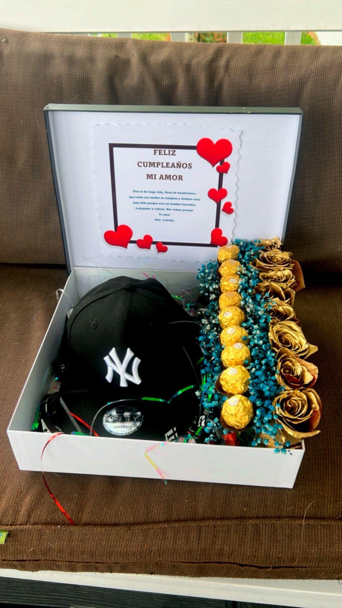 Cajita con gorra - Cajita de regalo elaborada con rosas pintadas de dorado, gipsofilia pintada de color azul, chocolates ferrero y gorra.