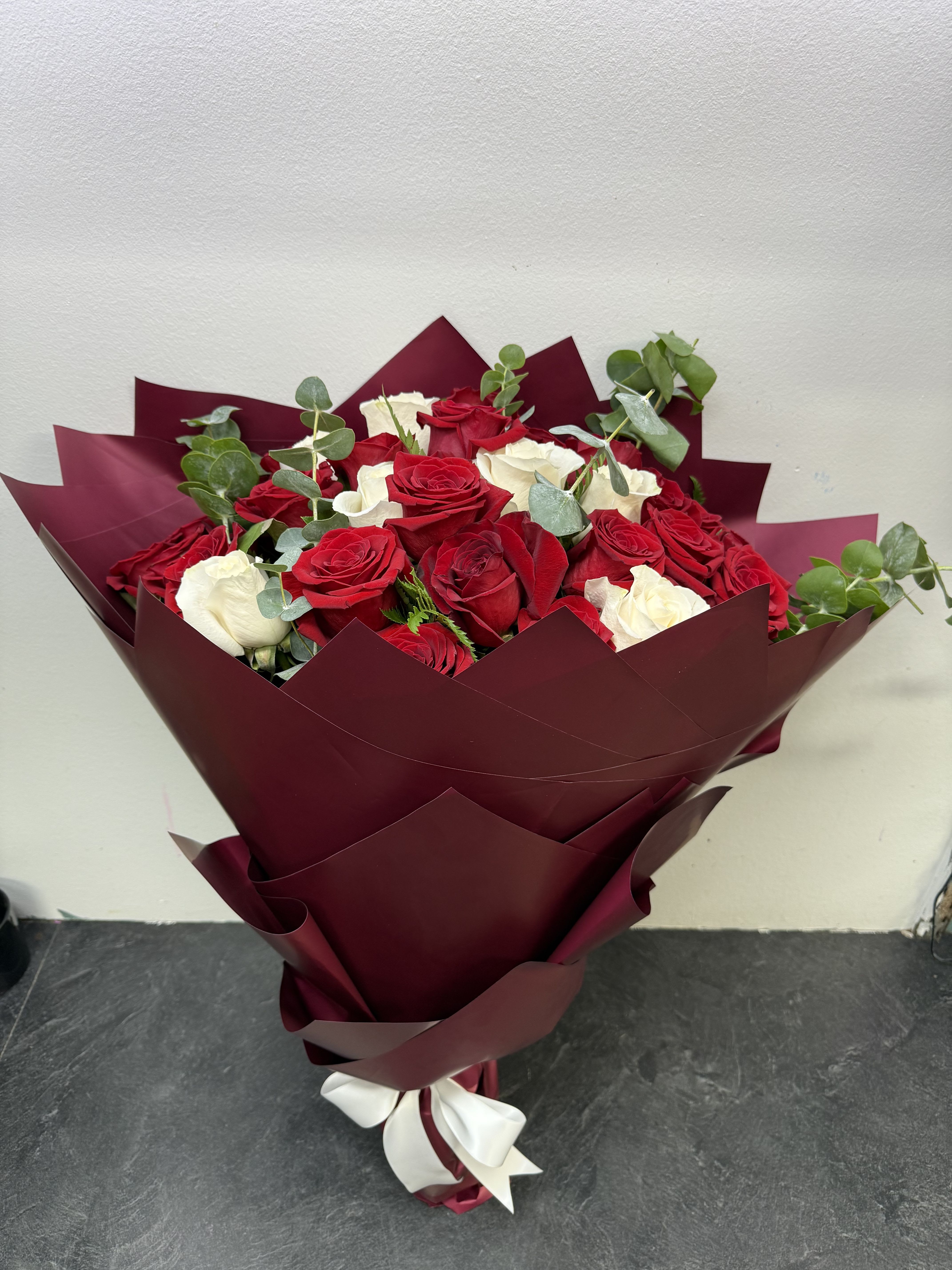 Timeless Love Timeless Love - A striking bouquet of velvety red and creamy white roses, beautifully accented with fresh eucalyptus for a touch of elegance. Wrapped in deep burgundy with a satin bow, this arrangement is a timeless symbol of passion and purity—perfect for anniversaries, romantic gestures, or unforgettable celebrations.
