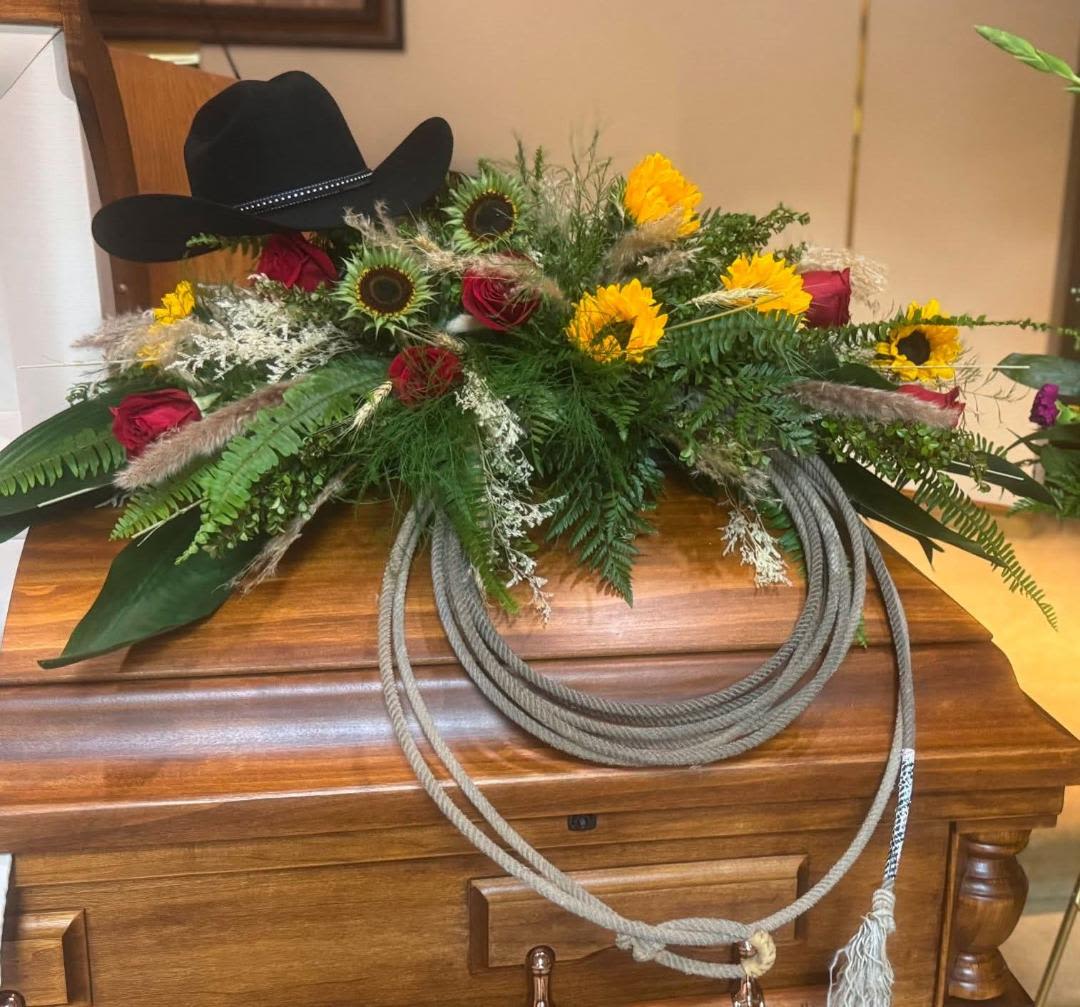 Mr. Garren - A lovely tribute to a great person that a loving display of a cowboy.  The red roses and sunflowers are stunning against the dark greens and a few dried flowers. (Hat and rope are not included.  An extra charge will be added for the rope)