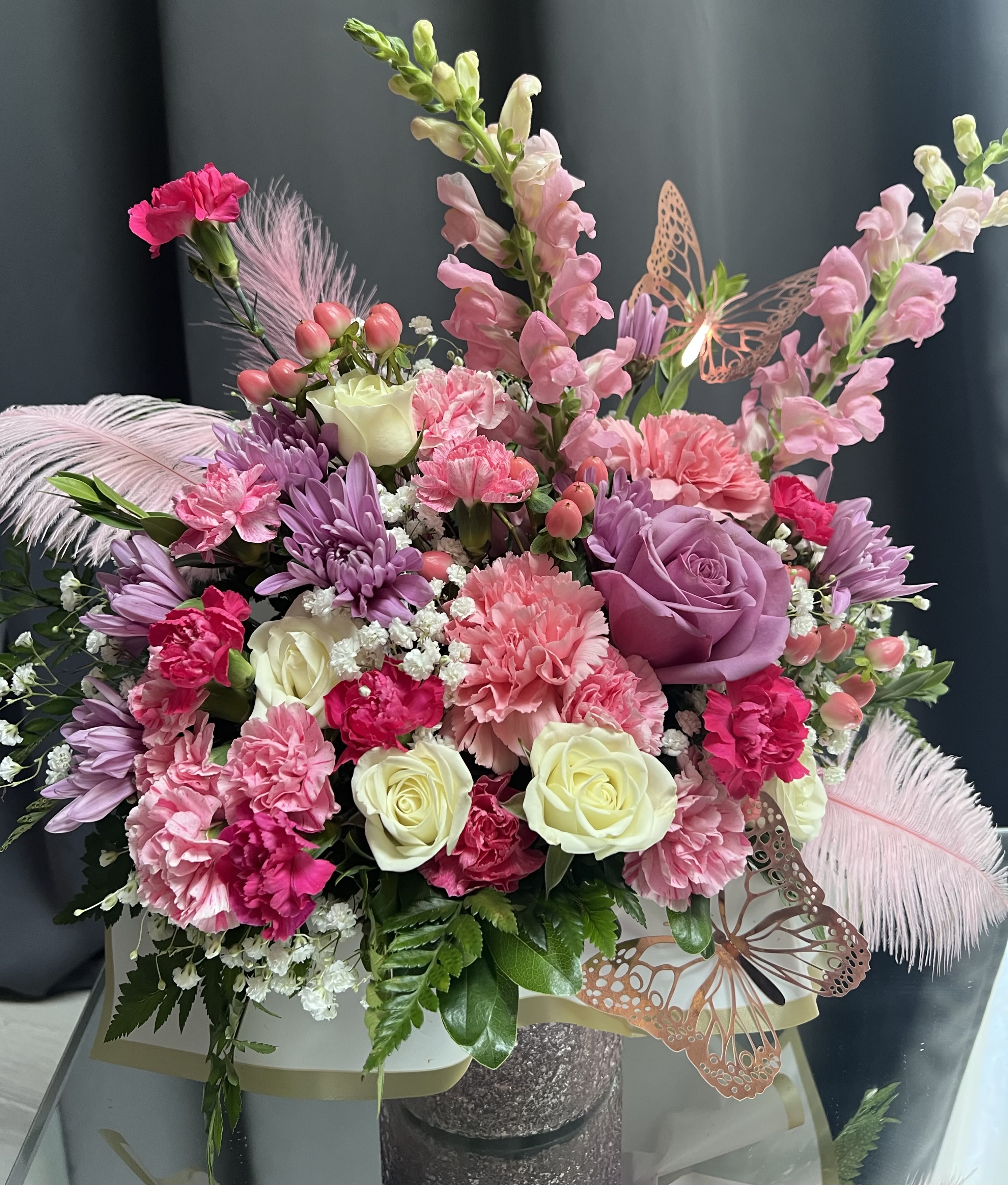 Baby Girl - Celebrate a newborn girl and her family in full color with this joyful luxury floral arrangement. Featuring a lush mix of creamy white roses, playful pink alstroemeria, vivid chrysanthemums, and delicate carnations, this design bursts with vibrant textures and all shades of pink &amp; lavander hues.  Accented with seasonal blooms, butterflies, and feathers, it arrives beautifully presented in a stylish lander container. Order today for the same day delivery in Hampton Roads. 