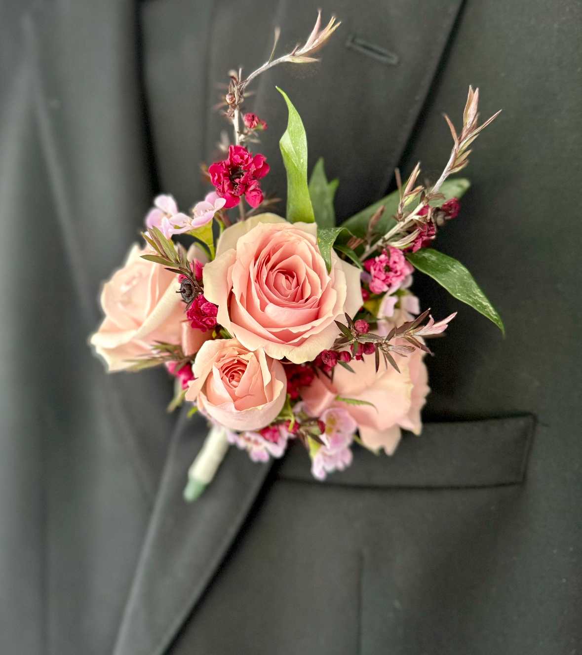 Lapel Boutonniere - A youthful and elegant design especially created by the Florist. Flowers are hand selected by the Florist. Perfect for weddings, prom, homecoming, and school dance.  Please specify preferred color theme in the Florist Instructions when ordering. Colors can be in White, Pink, Blue, Lavender, Orange, Red, Yellow, Green or No Preference.  Boutonnieres are wrapped in ivory ribbon (as pictured).  We highly advise ordering at least 2 days in advance to ensure availability of supplies for the Color Selection.  If your event falls on a weekend, choose Friday delivery. Boutonniere will stay fresh for a few days if kept in a fridge. Delivered in a waterproof box with clear plastic lid.