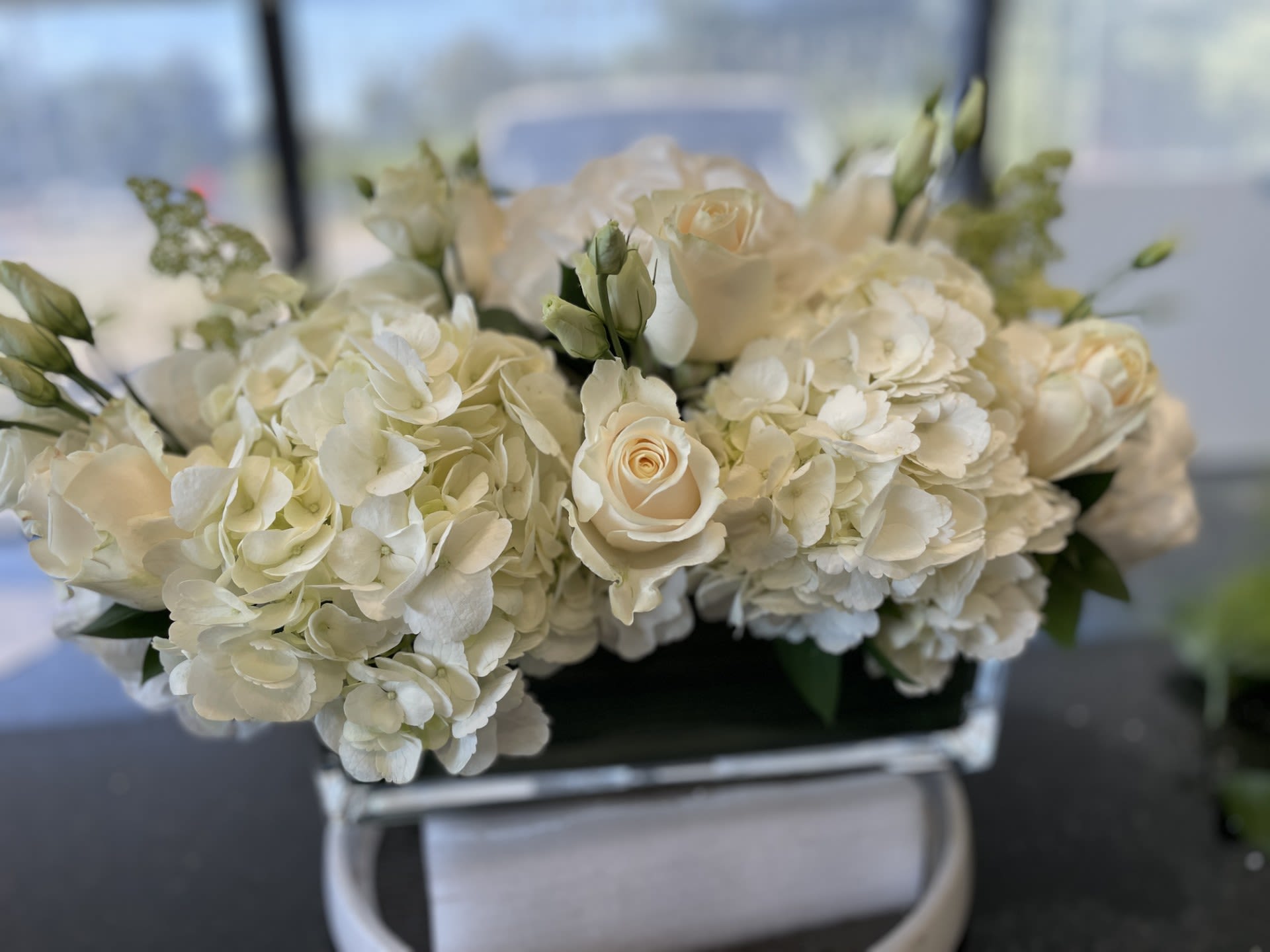 White Centerpiece - The perfect touch - All white Centerpiece , overall 17-18 inches long. - Made in 12 inch X 4 inch Glass Rectangle, standing over all about 10 inches tall, perfect for the table.  Featuring, Hydrangea - Roses - Lisianthus