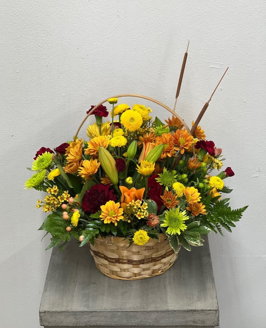 Apple Butter Basket - Assortment of warm fall colors such as deep burgundy, soft butterscotch, yellow, orange and touches of green arranged in a basket to bring in the fall into the home.  Flowers and colors may vary depending on availability. 