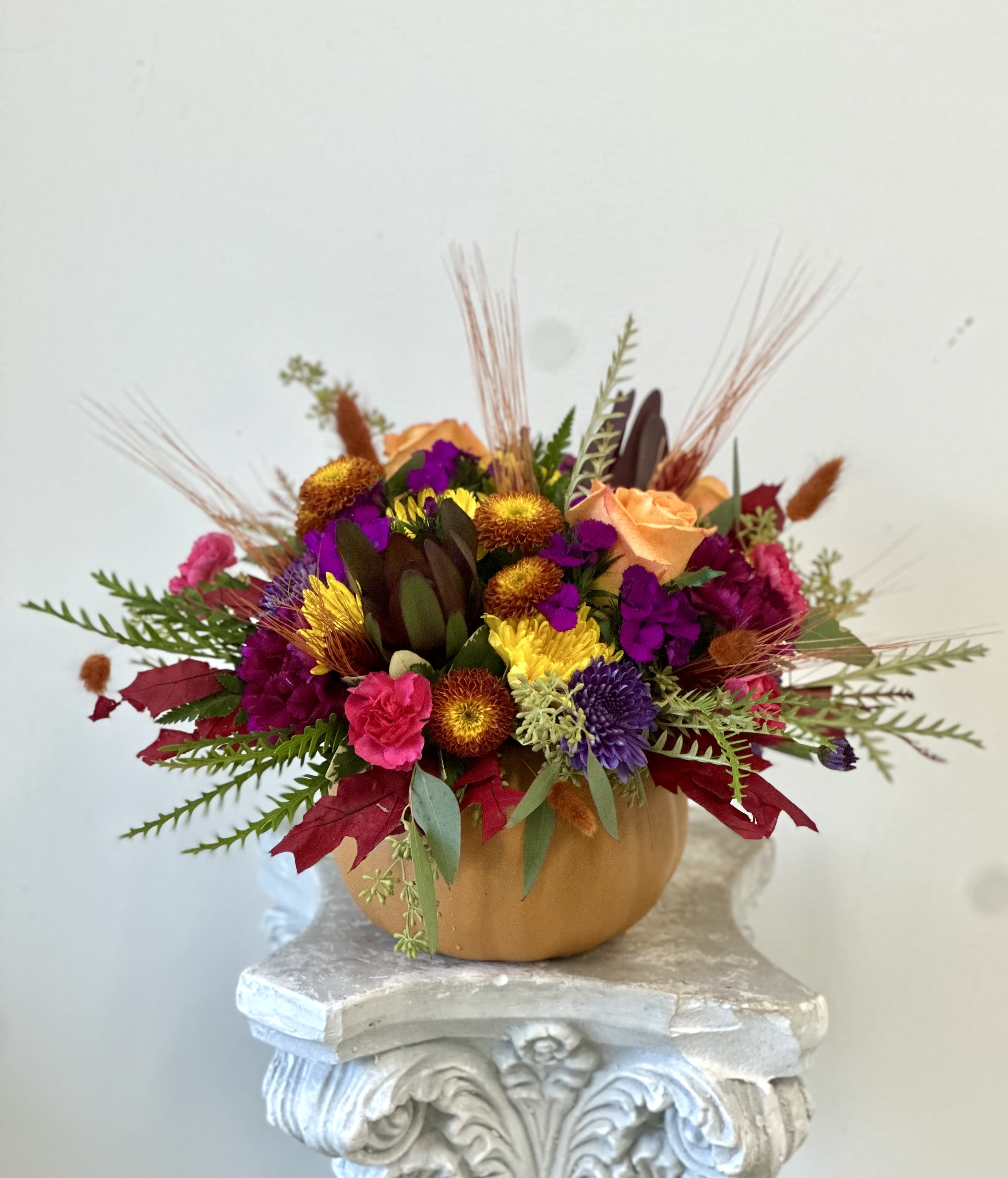 Fall Fiesta by Westford Florist - Embrace the warmth of autumn with Fall Fiesta by Westford Florist. This exquisite arrangement features elegant orange roses, vibrant fall poms, harmoniously blended with safari sunset blooms and magenta sweet William. Complemented by dry fall flowers and foliage, each element captures the essence of the season. Presented in a charming orange pumpkin vessel, this stunning bouquet not only serves as a centerpiece but also as a statement piece for any occasion. Whether celebrating Thanksgiving or simply brightening your home, Fall Fiesta is designed to bring joy and sophistication into your space. Experience the beauty of fall through this delightful floral masterpiece today.