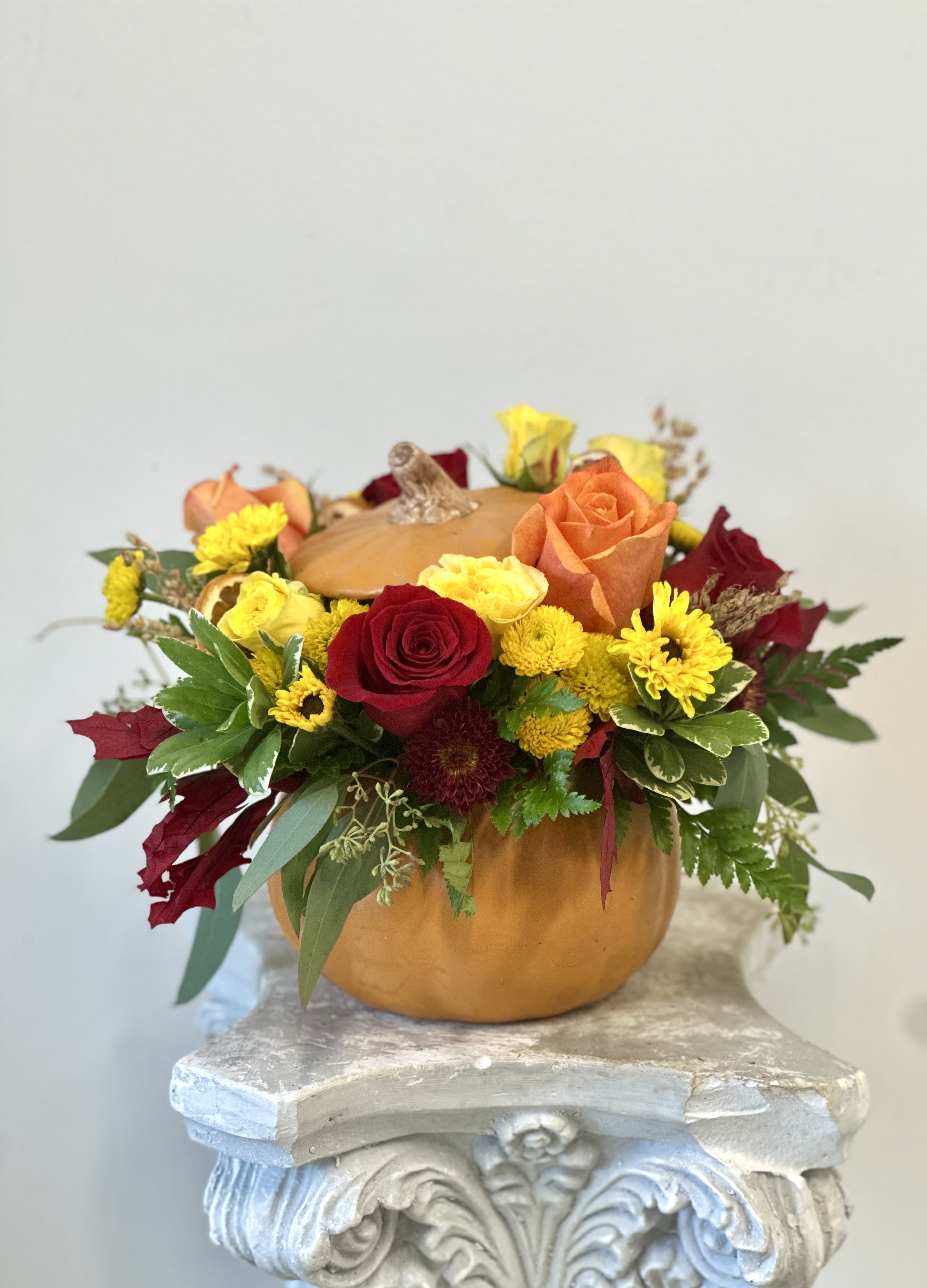 Autumn Splendor by Westford Florist - Embrace the essence of fall with **Autumn Splendor** by Westford Florist. This exquisite arrangement harmoniously blends elegant red and orange roses, cheerful yellow Viking poms, and vibrant yellow spray roses, all artfully nestled within a charming orange pumpkin adorned with a lid. The rich foliage and delicate greenery enhance this seasonal masterpiece, while accents of dried orange slices bring an inviting warmth to any setting. Perfect for celebrations or cozy gatherings, Autumn Splendor captures the brilliance of autumn's colors and fragrances, making it an ideal gift to brighten your loved ones' spaces or elevate your own décor. Elevate your surroundings with this stunning representation of nature’s bounty.