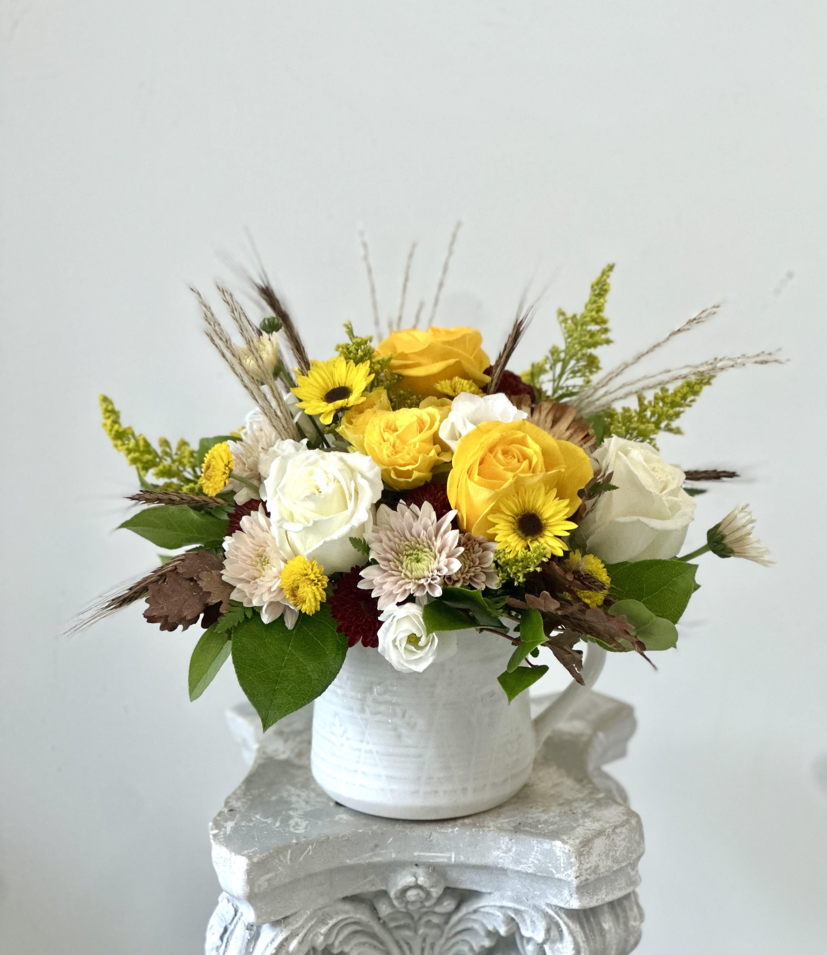 Golden Harvest by Westford Florist Art by Veny - Brighten your space with the enchanting Golden Harvest Arrangement by Westford Florist Art by Veny! This elegant bouquet features a delightful mix of white and yellow delicate roses, charming white lisianthus, and playful poms in peach, burgundy, and sunny yellow. Nestled among vibrant yellow solidago and lush fall foliage, this stunning arrangement is thoughtfully designed in a petite white ceramic container that adds a touch of sophistication to any setting. Perfect for sprucing up your home or surprising someone special, let this cheerful floral masterpiece bring warmth and joy into every corner! 