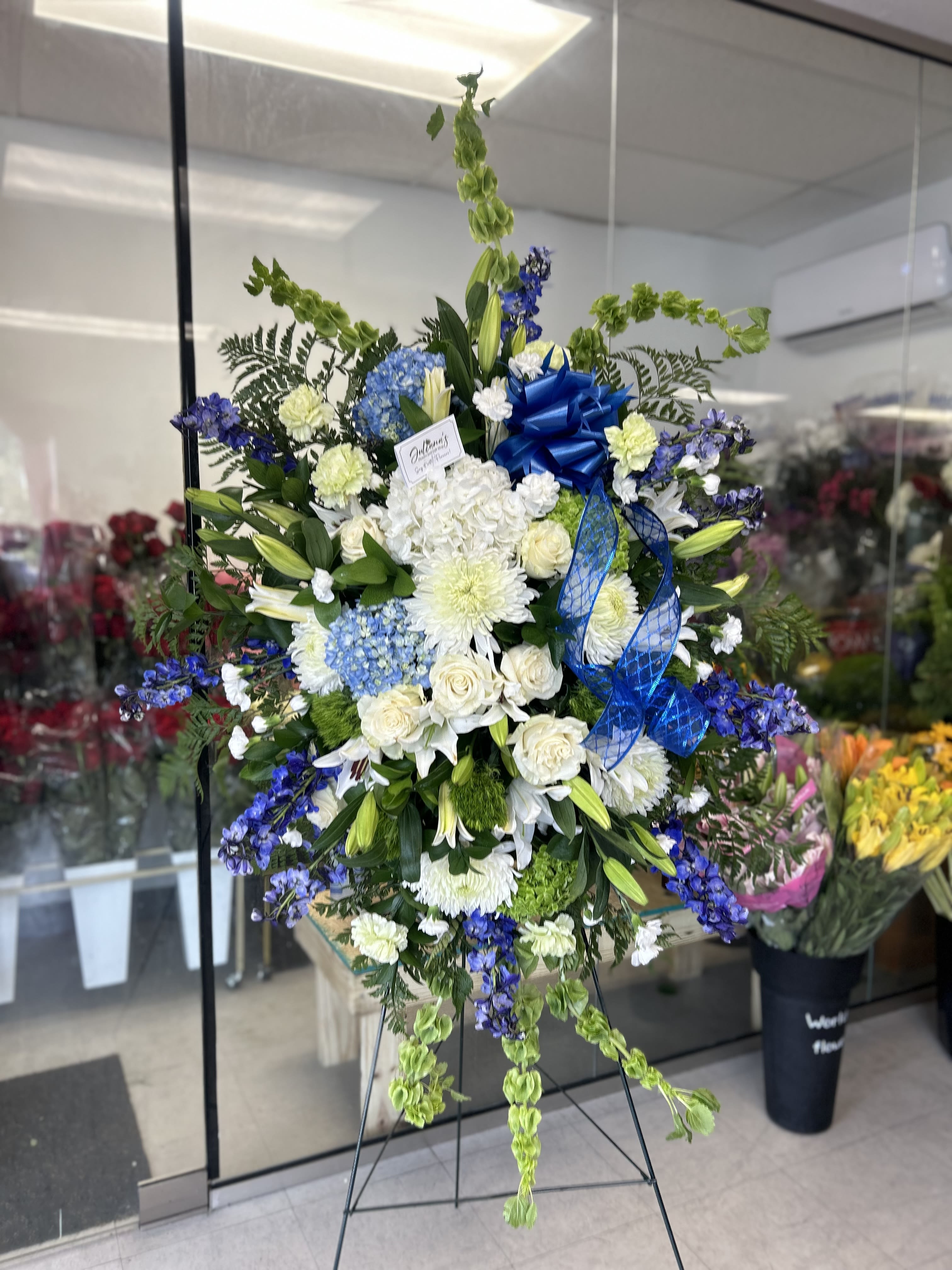 White and blue Standing spray  - Blue and white elegant funeral arrangements on a standing spray honoring the memories of a loved one at the wake, funeral or memorial services