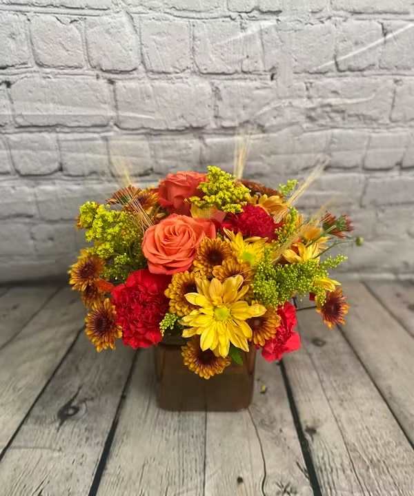 TRENDY AUTUMN TRENDY AUTUMN - Classy fall flowers nestled inside a clear glass cube for a fresh, modern look.
