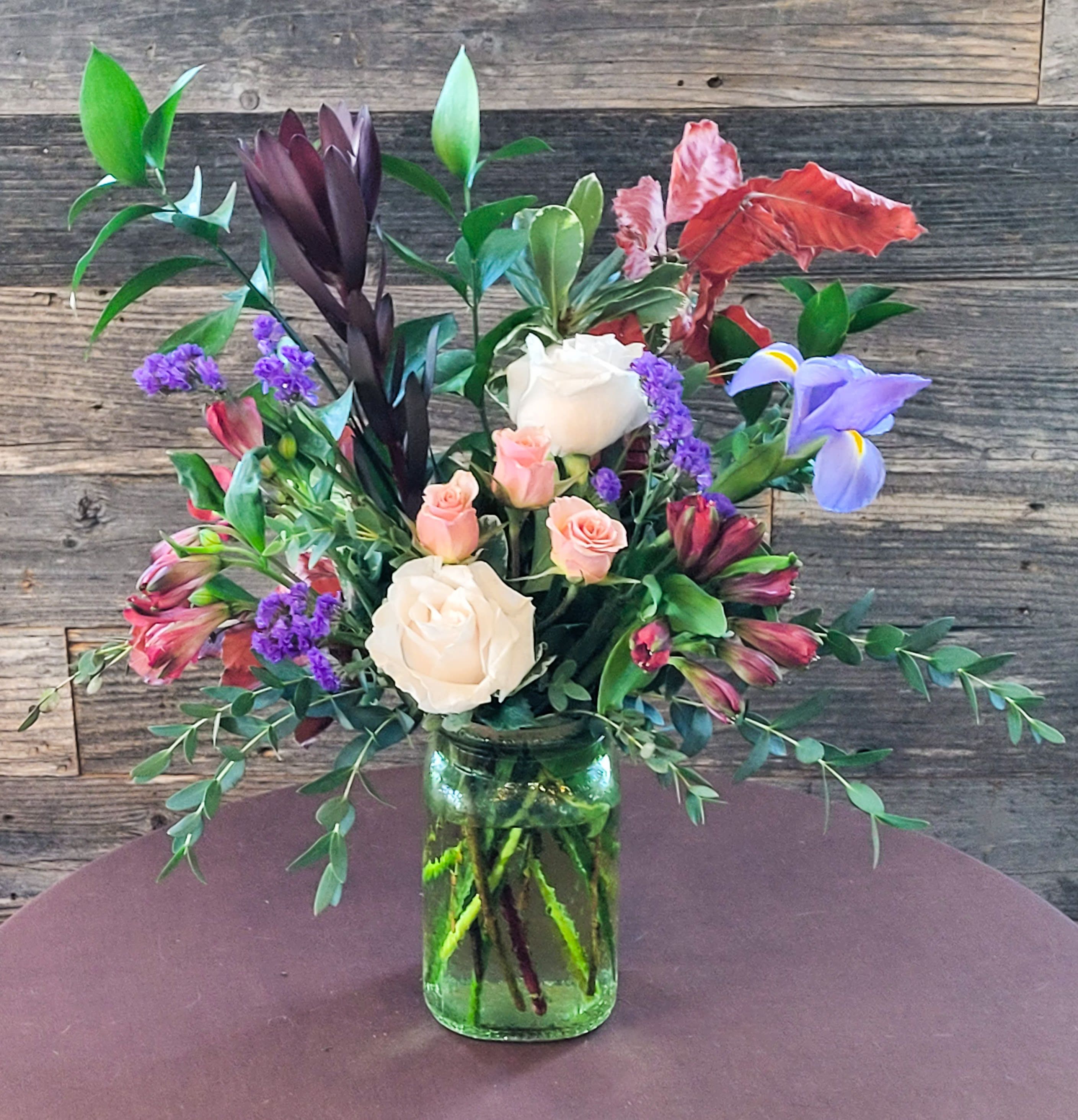 Wild Radiance - A dynamic arrangement of roses, tropical blooms, and lush greenery. 