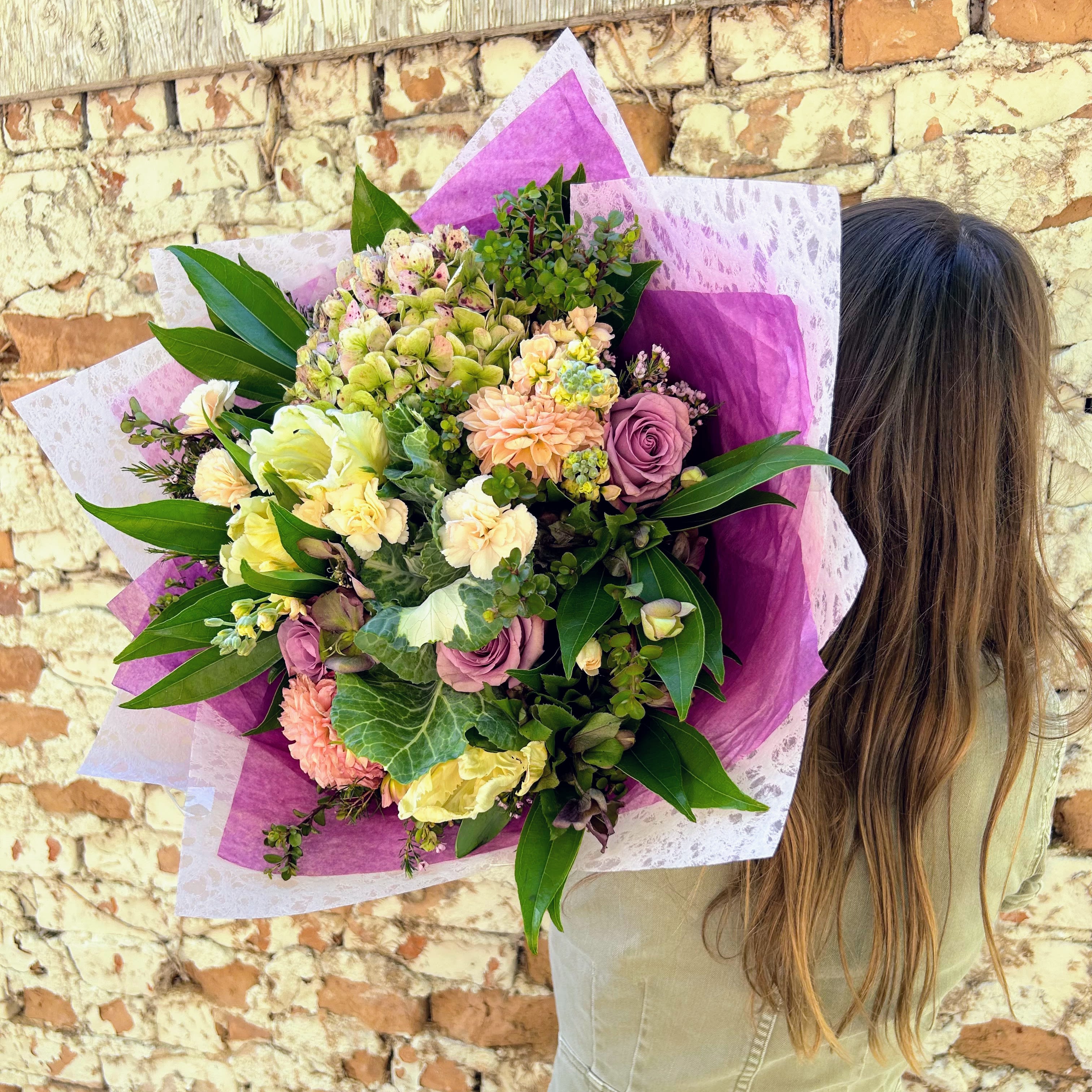 Lavendar Haze - A dreamy and earthy wrapped bouquet with premium antique hydrangea, kale, purple roses, and seasonal peach dahlias.