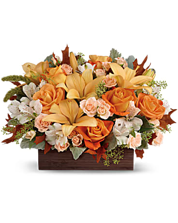 Teleflora's Fall Chic Bouquet - Simply chic and overflowing with fall blooms! This gorgeous centerpiece arrangement is sure to impress with its glorious shades of autumn - combining orange roses, peach lilies and seasonal brown leaves. Hand-delivered in a dark-toned bamboo rectangle. This impressive centerpiece arrangement features light orange and peach roses, peach asiatic lilies and white alstroemeria, and finished with dusty miller, seeded eucalyptus and millet. Delivered in Teleflora's Dark Bamboo Rectangle. Orientation: One-Sided
