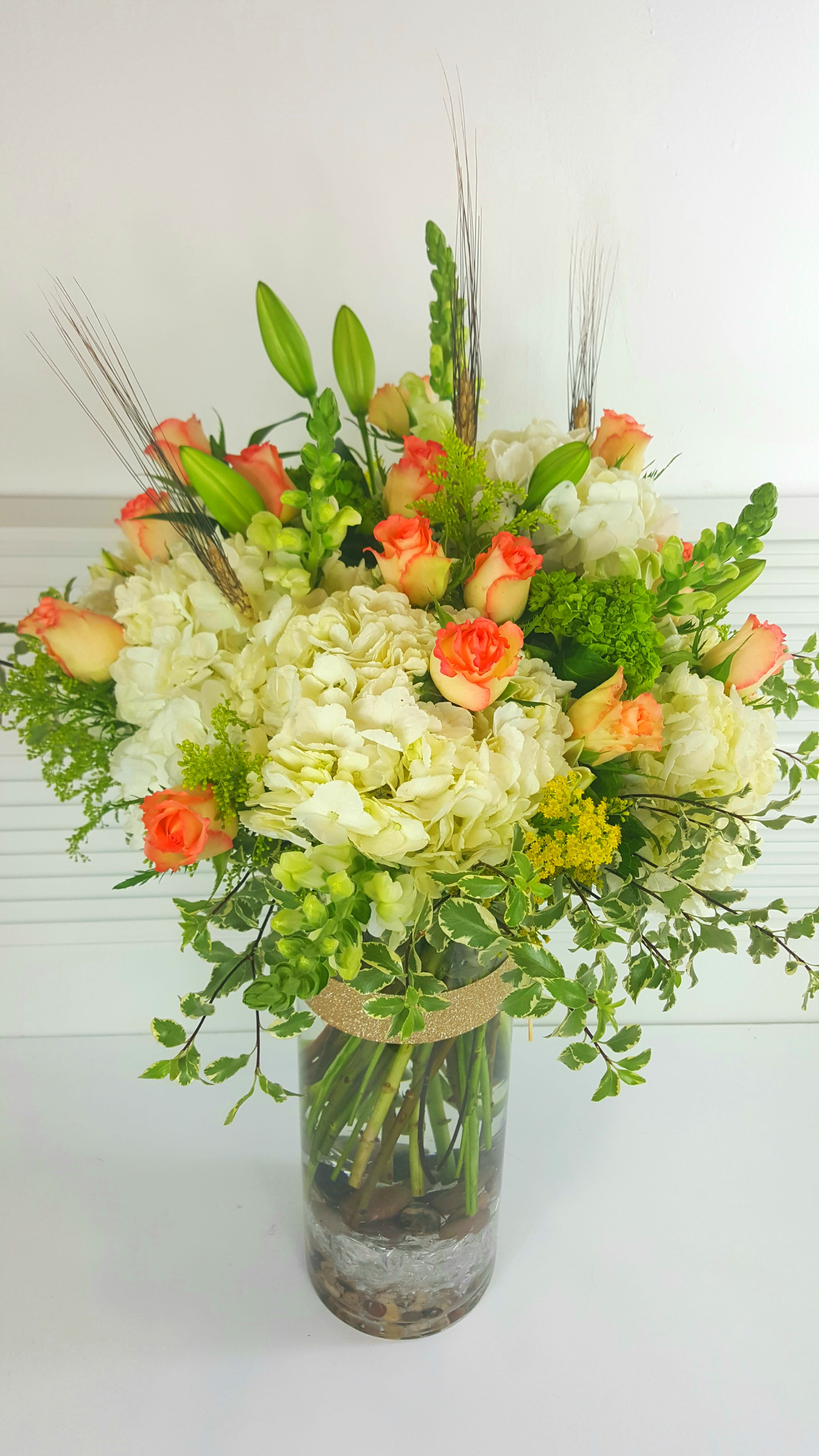 Mamma Mia!!! - Beverly Hills - Impressive tall arrangement in a 16&quot; cylinder clear vase field with white and green hydrangeas, peach african roses, lily, solidago, white snap and greenery. Overall size is about 26&quot; tall.