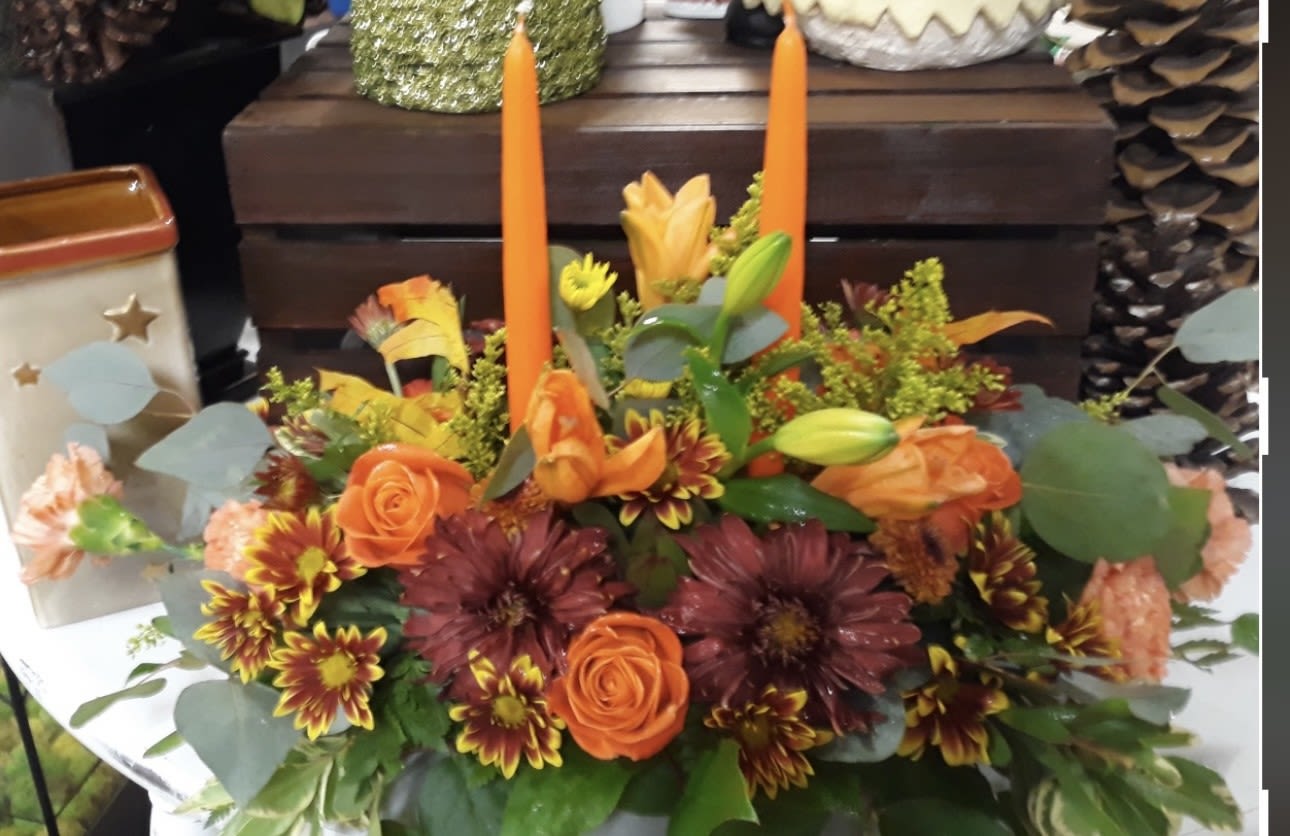 FALL FUN CENTERPIECE - MIX OF AUTUMN MUMS, LILLIES, ORANGE ROSES, MIXED GREENS WITH 2 TAPER CANDLES