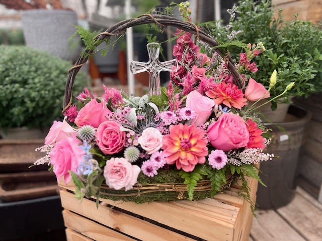 Peaceful Petals Peaceful Petals - This floral arrangement is a beautifully crafted, garden-style tribute piece, designed in a rustic grapevine basket with an arched handle and adorned with a clear glass cross — ideal for memorials, religious ceremonies, or expressions of sympathy and peace.