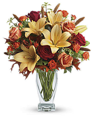  Fall Fantasia - Roses, lilies and oak leaves create a fantasy of fall flowers. Send this tall, elegant arrangement to wish someone a happy autumn or joyous Thanksgiving. The warm color palette and Couture Vase make a stylish seasonal statement. Orange, dark orange and red roses blend with orange asiatic lilies, green salal and pitta negra. Subtle seasonal elements include dried oak leaves and millet. Presented in Teleflora's chic Couture Vase. Orientation: One-Sided