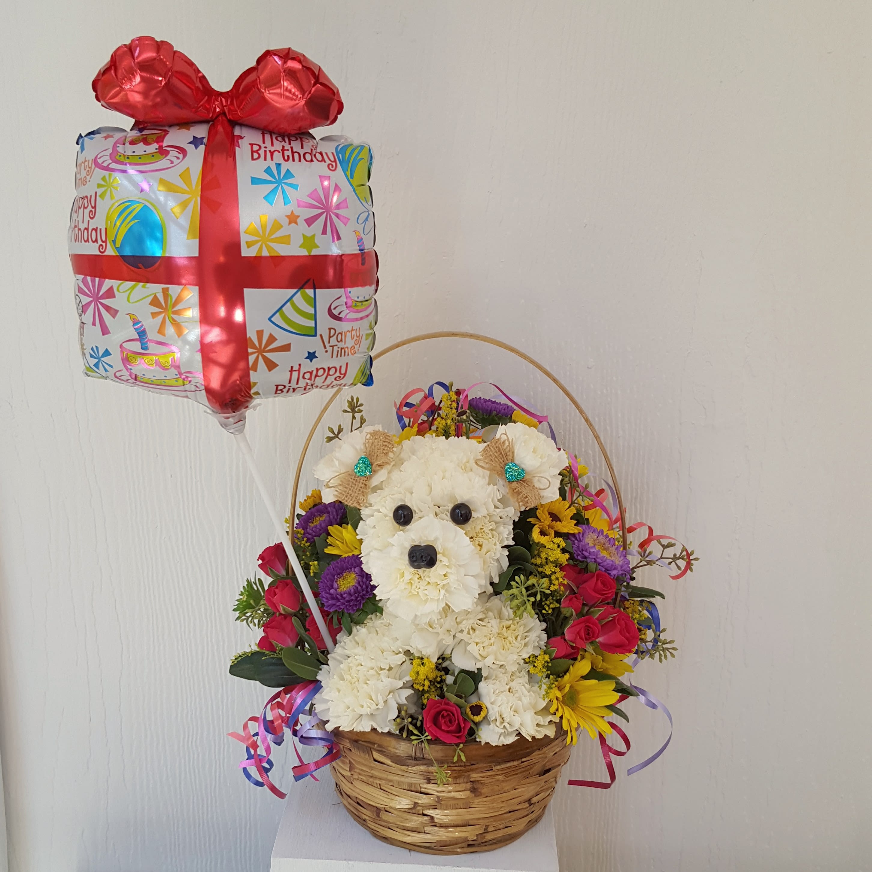 Party Time with Fifi - Send Fifi to deliver your birthday wishes! This fun and cute arrangement features Fifi holding a Happy Birthday Mylar Balloon. Height (to the top of the handle) is 15&quot; high. Upgrades of this item will mean you get an additional amount of flowers added to the design, currently shown is one sided. Fifi can be personalized for any occasion, call us to create your unique Fifi today! Floral selection, colors and Mylar balloon will vary in style depending on availability.  