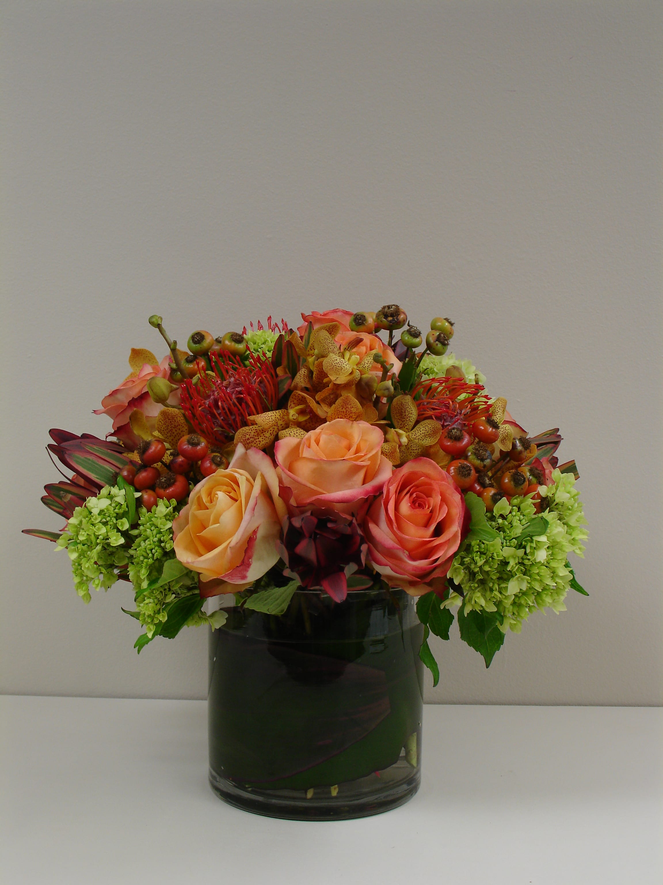 Rosehip Wonder - A beautiful arrangement featuring premium roses, mini green hydrangea, rosehip and complementary florals in a chic leaf wrapped vase.