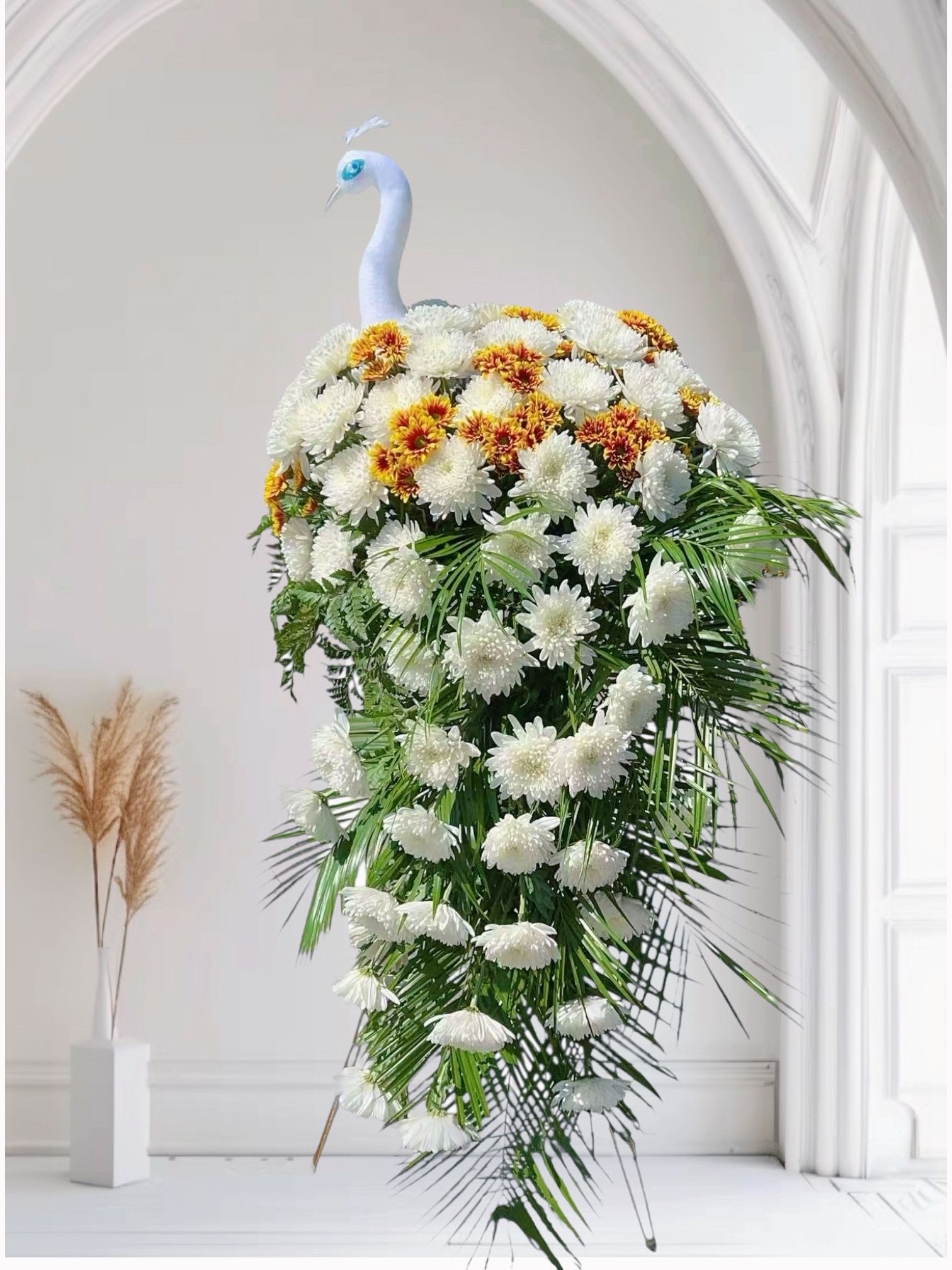 Eternal Guardian - The Eternal Guardian floral tribute embodies dignity, serenity, and everlasting remembrance. Designed in the elegant form of a white peacock, this arrangement symbolizes purity, nobility, and protection. Crafted with fresh white chrysanthemums and accented with golden-centered blooms, it creates a graceful cascade of blossoms, echoing the eternal watch of a guardian spirit.  Perfect for memorial ceremonies, funerals, and occasions of deep remembrance, Eternal Guardian conveys heartfelt respect, eternal love, and peaceful blessings.  Key Features: 	•	Shape: Elegant peacock design 	•	Main Flowers: White chrysanthemums, yellow-centered chrysanthemums, lush greenery 	•	Symbolism: Purity, nobility, eternal protection 	•	Ideal Occasion: Funerals, memorials, sympathy events