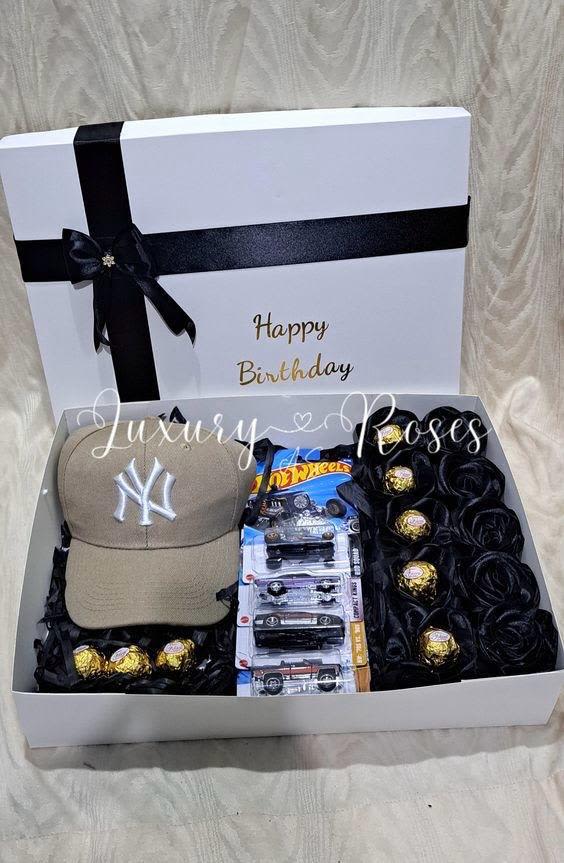 Cajitas para hombres - Caja para hombre elaborada con rosas eternas echas a mano color negro, hot wheels, chocolates ferrero y una cachucha.