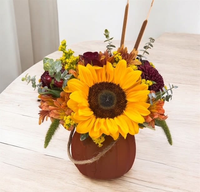 Gourd-geous Garden - Embrace the cozy charm of fall with this stunning arrangement, artfully displayed in a smoked glass pumpkin vase, available in both vibrant orange and serene sage green. This delightful design is a perfect blend of seasonal beauty, featuring cheerful sunflowers, rich fall-colored mums, and clusters of hypericum berries. The bouquet is further enhanced with an array of assorted autumn flowers, bringing warmth, color, and texture to your space. Whether you're celebrating the season or adding a touch of fall elegance to your home, this arrangement is sure to brighten any room with its rustic yet refined charm.