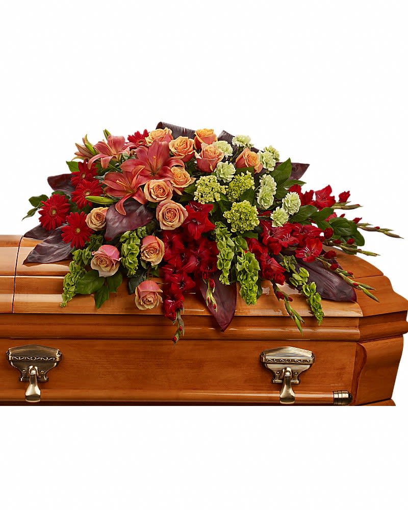 A Fond Farewell Casket Spray - An overflowing of love and respect is joyfully expressed in this truly magnificent casket spray of orange roses and lilies and other brilliant blooms. The magnificent arrangement includes green miniature hydrangea, orange roses, dark orange asiatic lilies, red gerberas, red gladioli, green carnations and bells of Ireland, accented with assorted greenery.