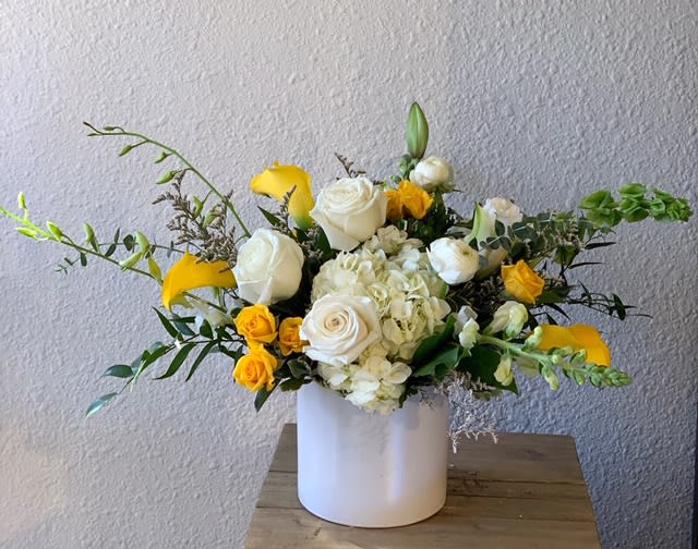Ray of Sunshine Ray of Sunshine - A beautiful white and yellow arrangement of Lilies, Orchids, Ranunculus, Roses, Hydrangea and more arranged in a keepsake cylinder ceramic vase.Your arrangement will be designed in the style shown but flowers and containers may be different from that pictured.