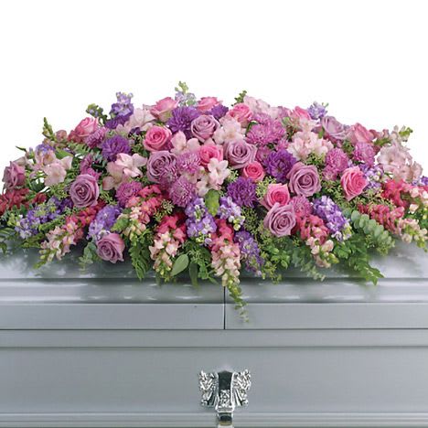 Lavender Tribute Casket Spray - Honor her femininity and generous spirit with a blanket of sweetly scented lavender, pink and purple flowers that create a magnificent final tribute, sincerely expressing devotion and love. Gorgeous flowers such as lavender and pink roses, pink snapdragons and alstroemeria, purple and lavender chrysanthemums. All are entwined with eucalyptus, huckleberry and ming fern.