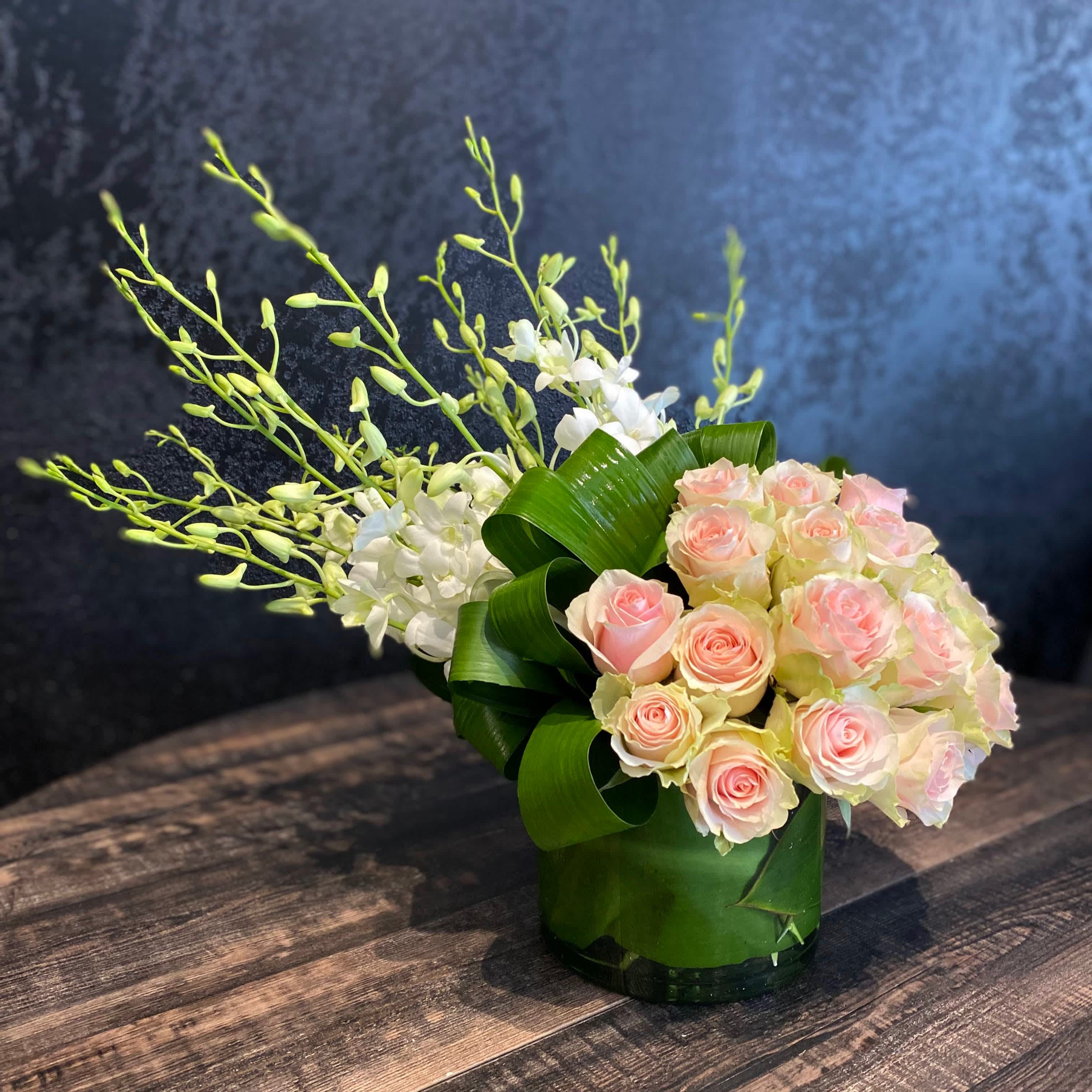 N.Y. - This design holds a certain powerful quality that really makes a statement in any room.  Colorful roses juxtaposed by stunning white dendrobium orchids accentuate each other so nicely. Color varieties are available. Made in a 6&quot; glass cylinder or cube.