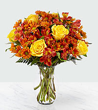 Golden Autumn Vase - This radiant bouquet is beautiful and complex, just like the season itself. Made up of yellow roses, bronze daisy pompons, and red alstroemeria, set in a clear glass vase, the Golden Autumn bouquet truly brings out the best of fall. 