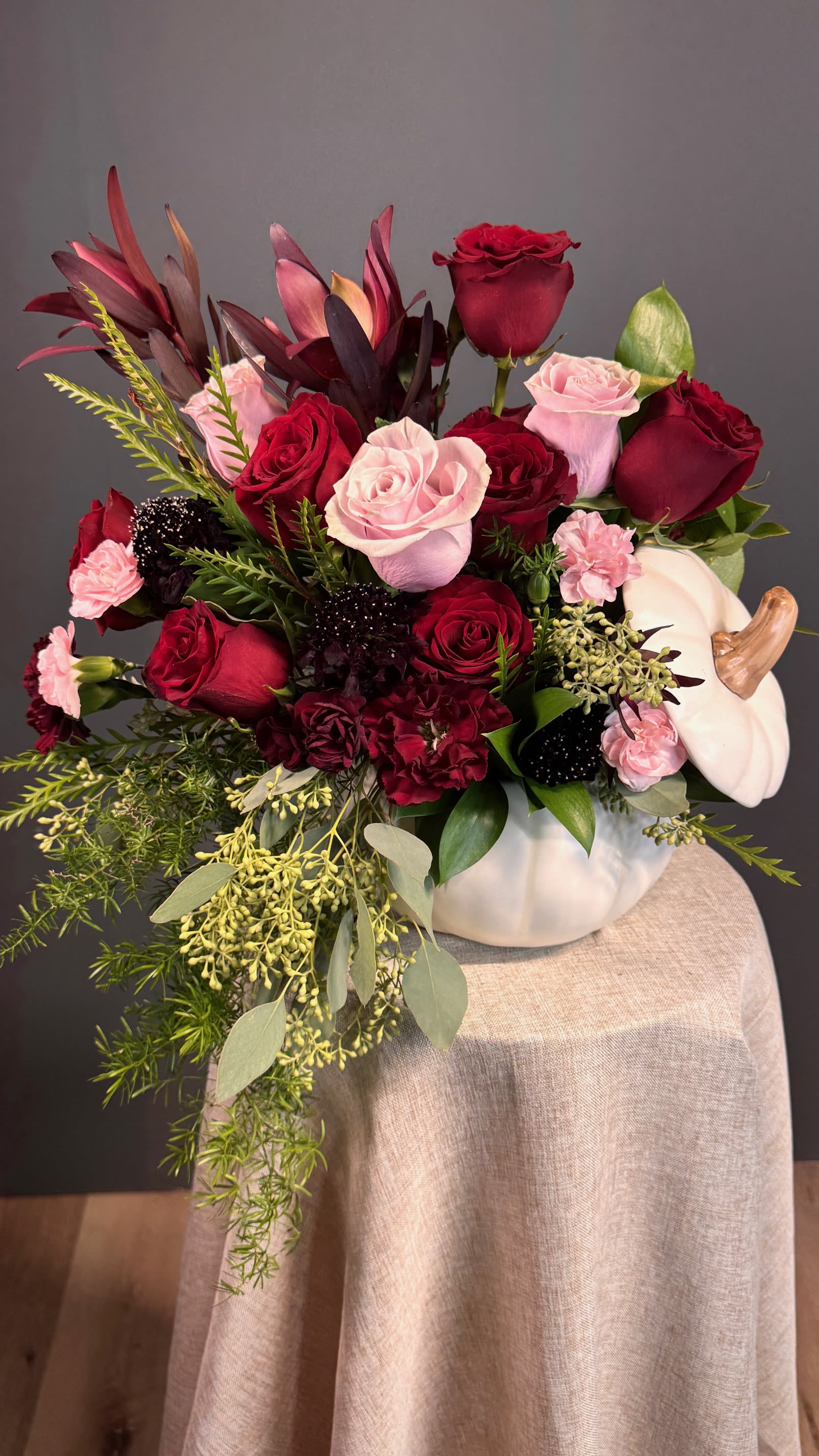 Autumn Elegance - A sophisticated mix of deep red and blush blooms, artfully arranged in a chic white pumpkin vase. Perfect for adding seasonal charm with a romantic twist.