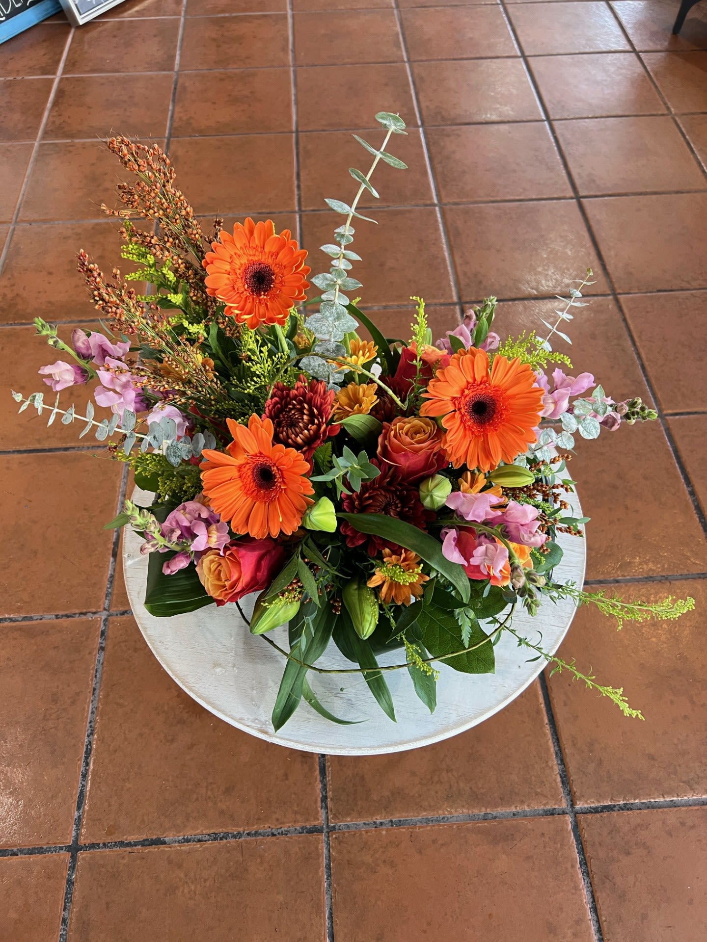 Autumn Garden - A beautiful fall arrangement for the autumn seasons. With stunning fall coloured gerbera daisies, solidago, chrysanthemums, snap dragons, broom grass, roses, and spray mums you will enhance any space with cozy autumn vibes.  ** Substitutions may occur based on fall flowers in stock at the time of purchase.**