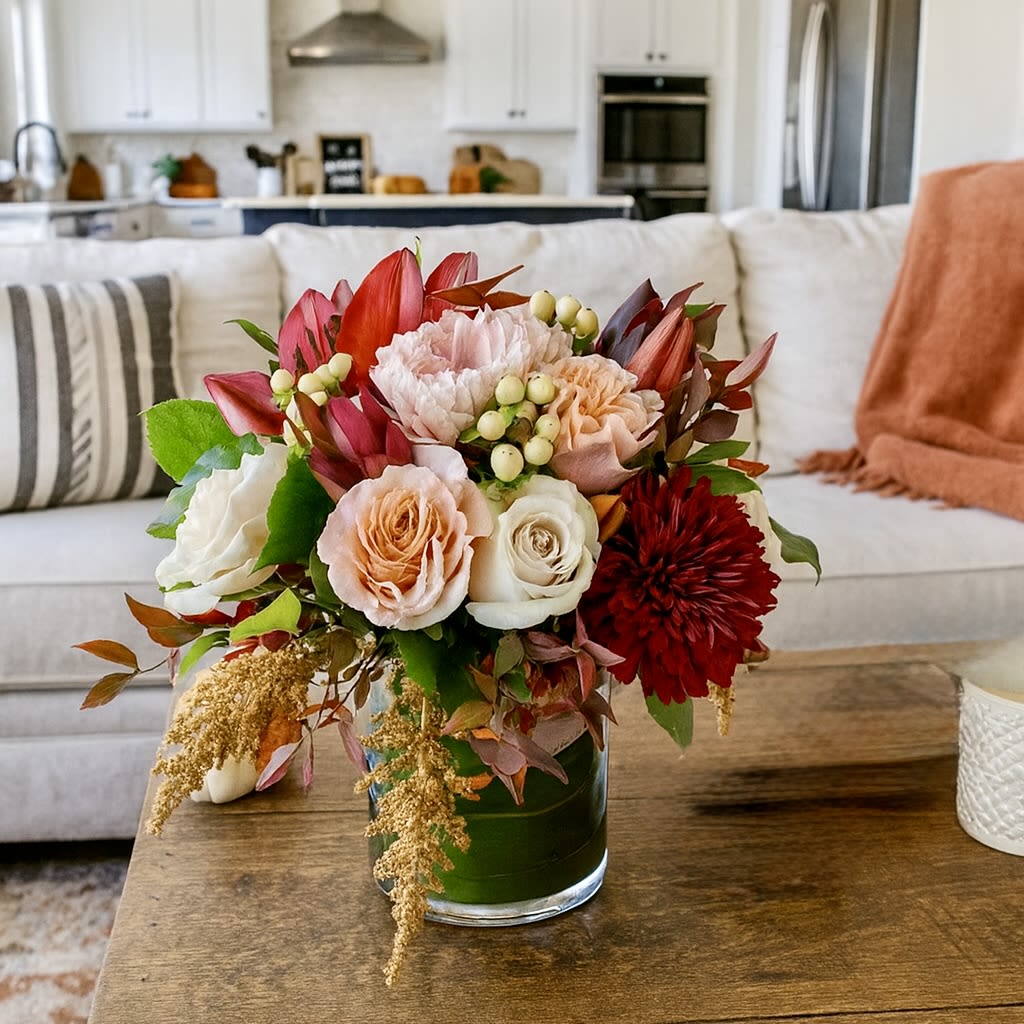 Farmhouse - Seasonal Fall Bouquet  - Farmhouse Arrangement – Rustic Elegance in a Vase  Bring the charm of farmhouse style into your home with our Farmhouse floral arrangement, a stunning mix of timeless blooms. Featuring soft cream and quicksand roses, bold burgundy lilies, lush dahlias, and fresh greenery, this design blends elegance with rustic warmth. Presented in a sleek cylinder vase, it’s perfect as a centerpiece, a heartfelt gift, or a beautiful addition to any modern farmhouse décor. Whether for celebrations, everyday beauty, or seasonal style, the Farmhouse arrangement delivers natural sophistication that never goes out of season.
