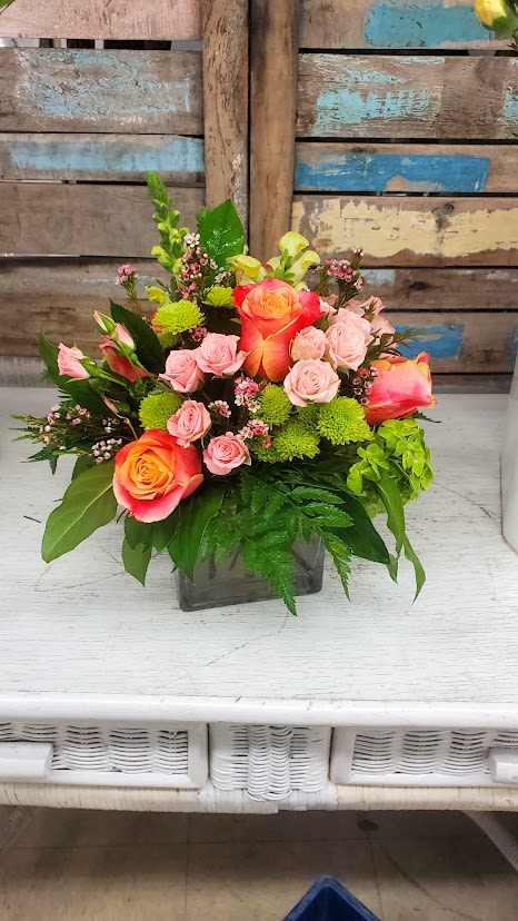 Hello Beautiful Hello Beautiful - Bright and cheery arrangement in a square cube with Roses, Spray Roses, Hydrangea, Snap Dragons and Wax Flower. *Color of Roses may vary*
