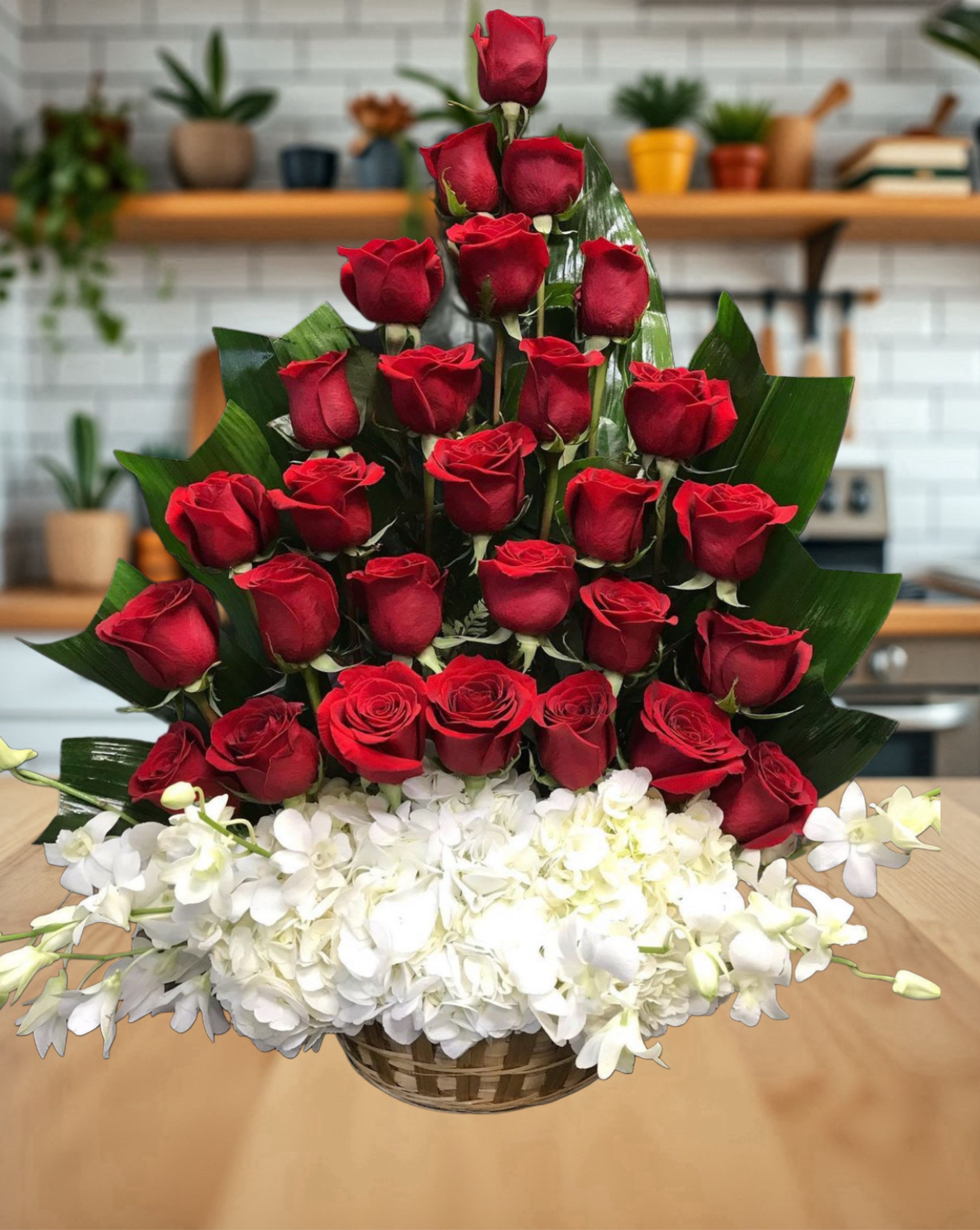 Eternal Love Basket - This striking arrangement features a luxurious cascade of deep red roses arranged in a pyramid style, symbolizing passion and devotion. The roses are beautifully complemented by a lush bed of pure white orchids and hydrangeas at the base, representing grace and purity. Styled in a woven basket with glossy green leaves for structure, this elegant design makes a powerful statement of love, admiration, and timeless elegance for any special occasion.