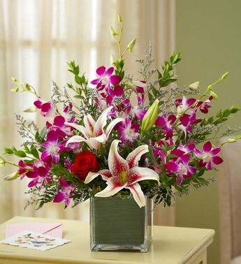 Deep Passion - EXCLUSIVE Send the perfect balance of romance and style with this picturesque bouquet of lush blooms. Deep purple orchids, red roses, elegant Stargazer lilies and misty blue are gathered by our florists inside a modern cube vase, ready to express your passion in a truly original way, no matter what the occasion. Luxurious bouquet of purple orchids, red roses, Stargazer lilies and misty blue