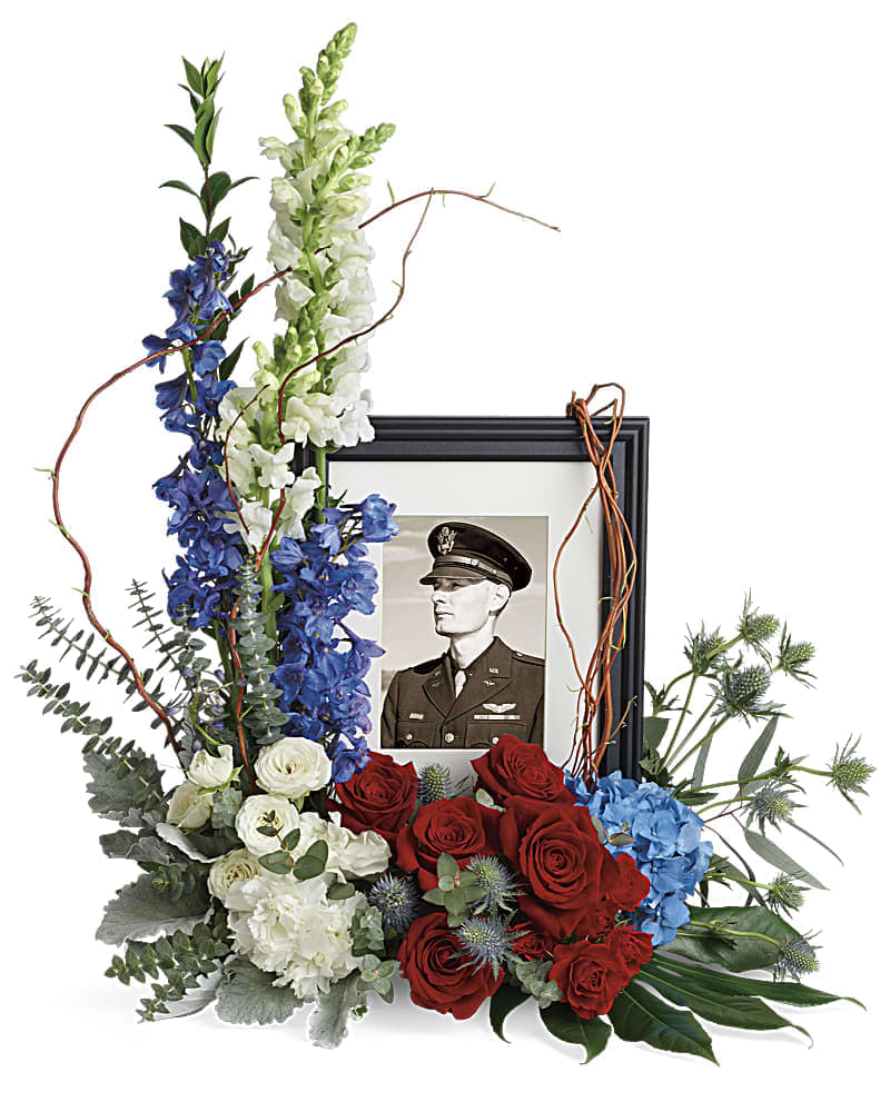 Always With Us Photo Tribute Bouquet - Honor the memory of an always-beloved with this beautiful display bouquet. Designed to surround a favorite photo, its patriotic mix of blue hydrangea with red and white roses is a respectful tribute. This bouquet features blue hydrangea, red roses, red spray roses, white spray roses, white carnations, blue delphinium, white snapdragons, blue eryngium, dusty miller, curly willow, spiral eucalyptus, parvifolia eucalyptus, aralia leaf and lemon leaf. Arrangement does not include picture frame.