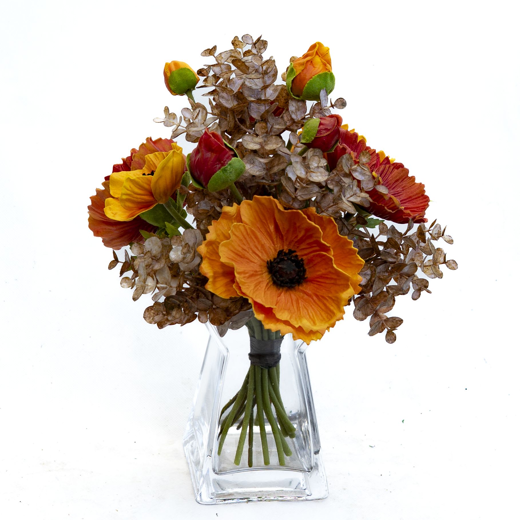 Rustic Sunset Bouquet (artificial) - This striking arrangement features bold orange poppies and tulip-like blooms accented with warm brown eucalyptus, creating a perfect balance of color and texture. Displayed in a sleek clear glass vase, the bouquet evokes the rich tones of a glowing autumn sunset, making it a stunning choice for seasonal décor or as a thoughtful gift.
