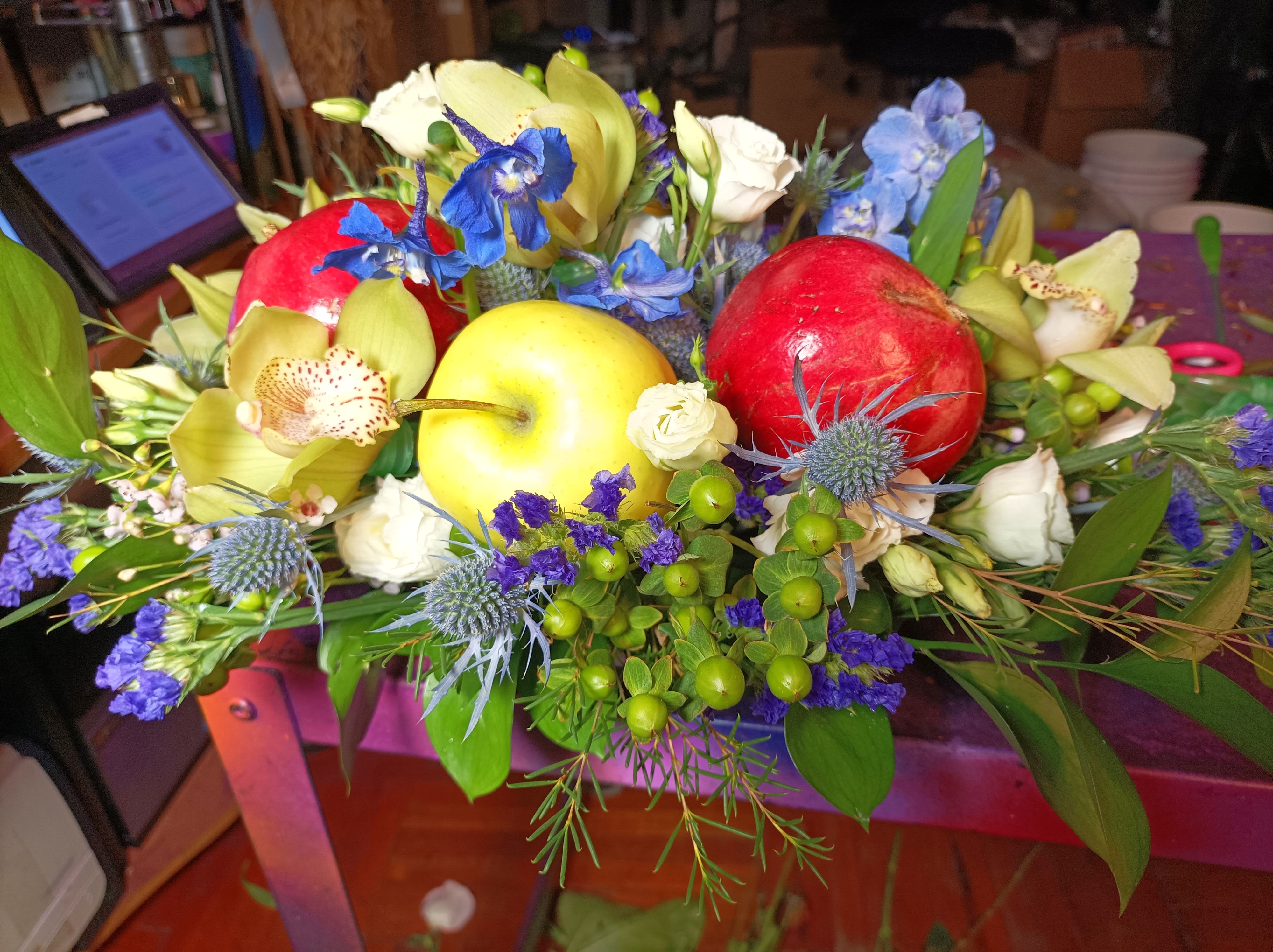 Rosh hashanah New years centerpiece  - A beautiful low centered centerpiece for the dinner table to celebrate the new year. Shana Tova️ Flowers and fruit. Pomegranates and apples, orchids and a beautiful mix of blue and white flowers.