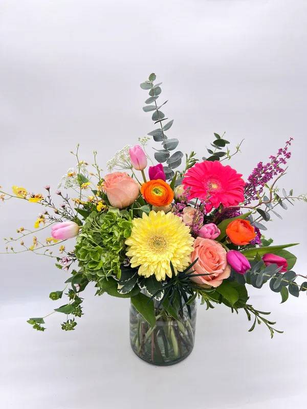 Warmer Days Ahead Warmer Days Ahead - Medium sized arrangement in a milk jug vase. Bright and colorful spring flowers. Designers may need to implement substitutions, however will follow the general arrangement style and color theme. Standard price point is pictured.