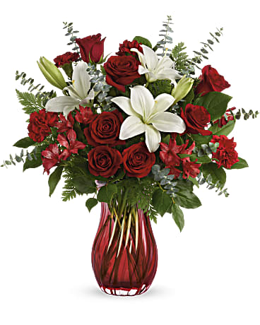 Teleflora's Love Conquers All Bouquet - Give Valentine's Day a dramatic twist with this romantic, swirling glass vase. Its ruby red ombre hue is the perfect complement for ravishing red roses and snow white lilies. Red roses, white asiatic lilies, red alstroemeria and red carnations are arranged with spiral eucalyptus, leatherleaf fern and lemon leaf. Delivered in Teleflora's Love Conquers All vase. Orientation: All-Around