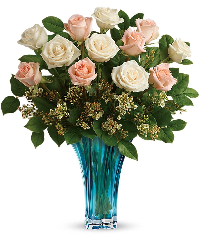 Teleflora's Ocean Of Roses Bouquet - Mom's a rose! Spoil her on Mother's Day with this breathtaking bouquet of 12 roses, hand-arranged in a swirling keepsake vase of blown glass, in the most elegant shade of azure blue. This beautiful mix includes 6 peach roses, 6 white roses, white waxflower, and lemon leaf. Delivered in a Heart's Pirouette vase.