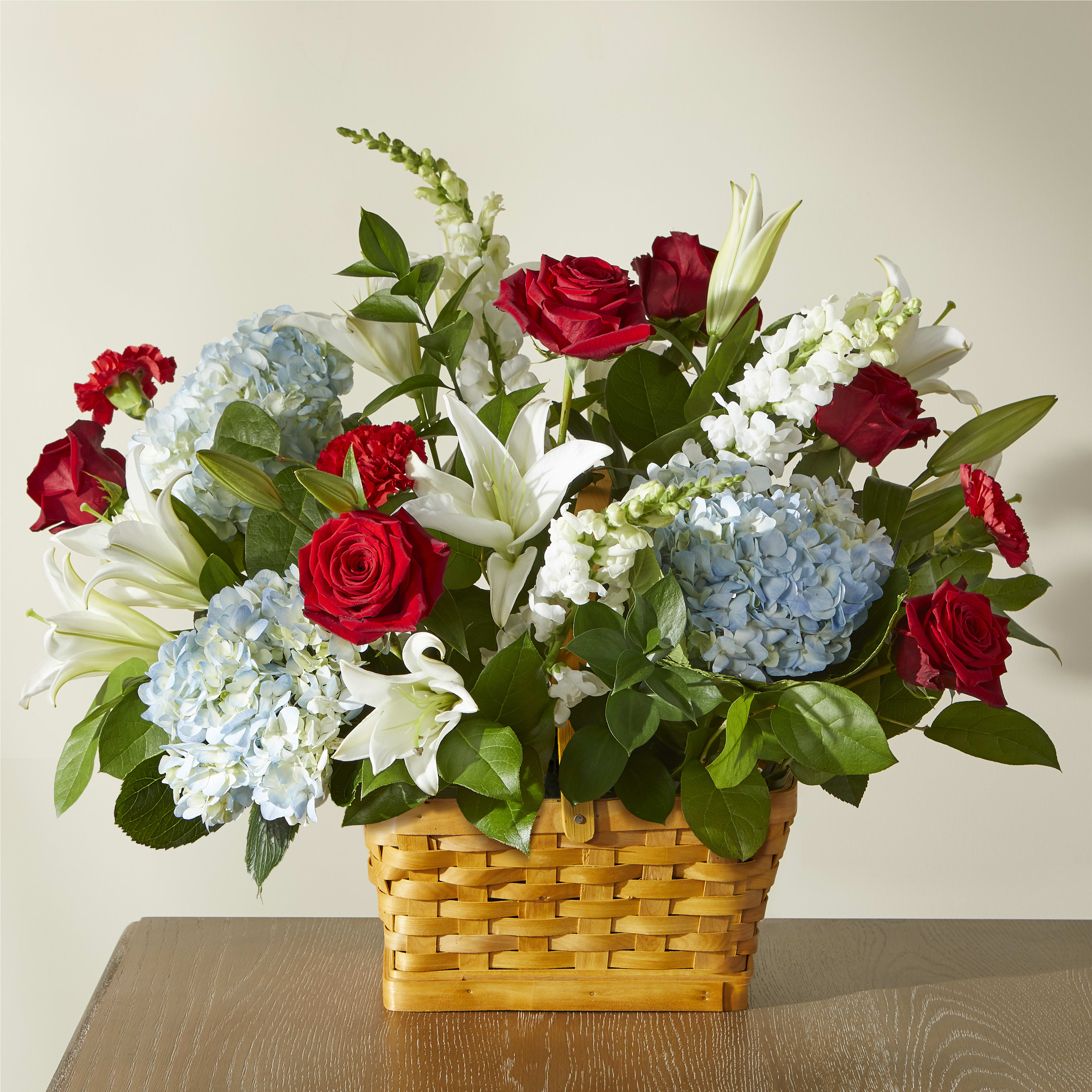 Red White and Blue Basket Arrangement Red White and Blue Basket Arrangement - Assortment of red, white, and blue flowers with greenery. Standard option is pictured. May vary from photo.