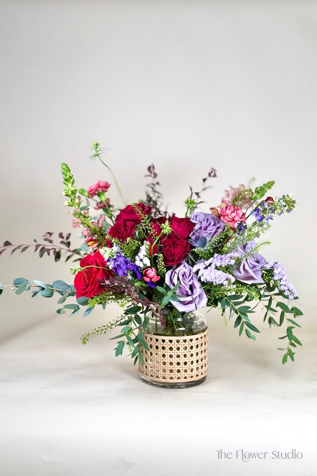 Monets Monets - Bright and cheerful, this garden-inspired arrangement bursts with vibrant yellows and striking blues. Featuring golden roses, gerbera daisies, and seasonal blooms paired with lush greenery, it’s beautifully designed in a clear glass vase with a woven accent wrap. Perfect for birthdays, celebrations, or simply bringing a touch of sunshine indoors, this arrangement radiates happiness and charm. Approx. 15" H x 20" W Our floral artists hand-design each arrangement, so flower and container styles may vary based on local and seasonal availability. As a result, we are unable to guarantee specific florals, colors, or vessels—but we always ensure the same level of beauty and value in every piece.