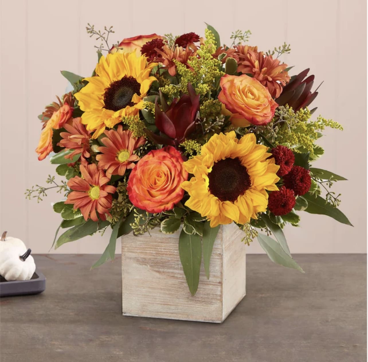 Harvest Glow - The color and charm of an autumn country harvest inspired our farmhouse-style bouquet. A loose, natural gathering of blooms in vibrant shades of red, orange and yellow creates the perfect complement to our rustic, grey-washed wooden cube. With its soft tones and natural textures, it’s an ideal container for flowers and plants, adding warm and coziness to any fall décor.  PLEASE NOTE: Florist reserves the right to make modifications to the design based on seasonality and accessibility of blooms and vases. Any modifications made will honor the palette, intent, and feeling of the pictured design. Contact floral designer directly with any specifications or concerns.