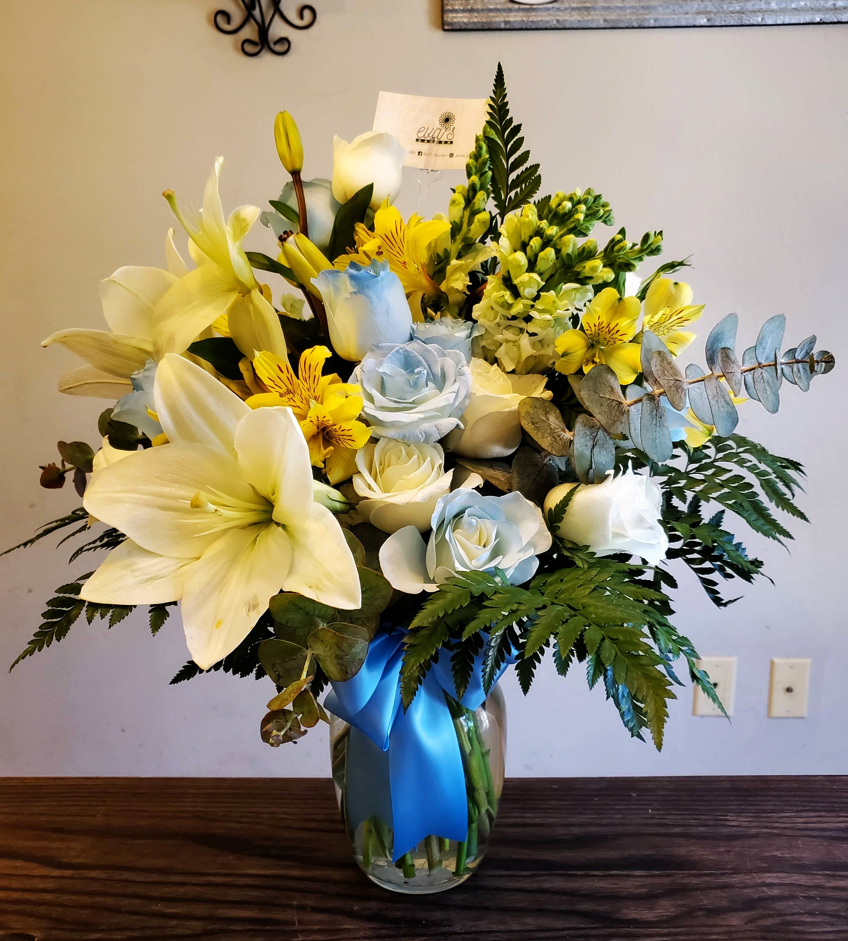 Sunshine in the Sky - Crystal vase with a mix of 12 blue &amp; white roses, 5 yellow snapdragons, 2 stems of white lilies, 6 yellow alstroemeria, leather leaf, and spiral eucalyptus.  (Picture depicts a premium product; standard &amp; deluxe size available upon request)