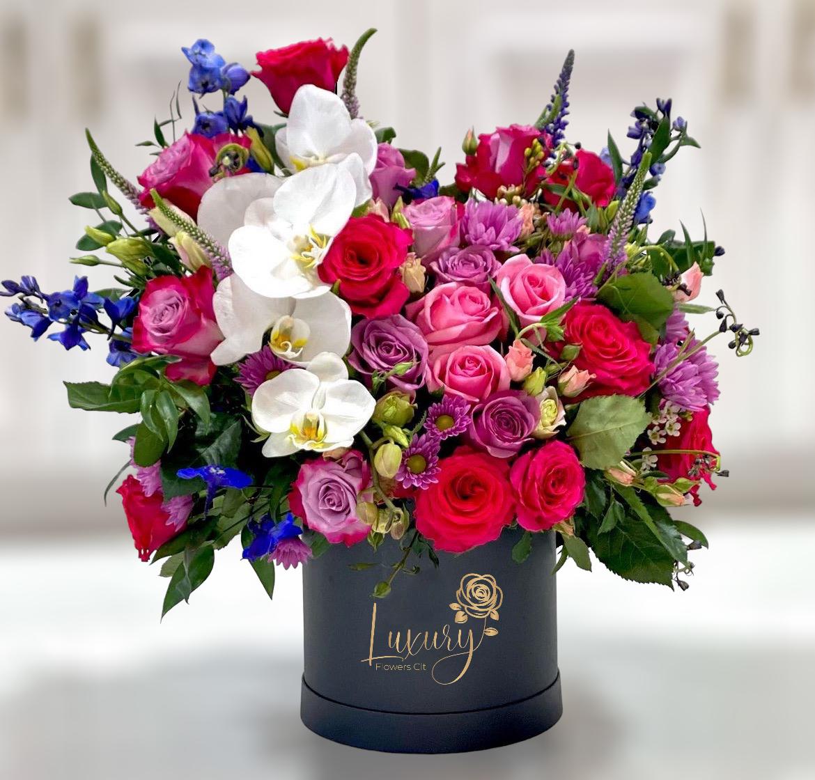 Belinda  - &quot;PLACE YOUR ORDER AT LEAST 2 DAYS PRIOR TO THE DELIVERY DATE”  This incredible box with a beautiful floral mix that includes Colombian roses, veronicas, spray roses, delphinium, and a mix of seasonal foliage, with an elegant orchid, is sure to be a spectacle at your next event or special occasion.   6” Black Cylinder Container All Occasion Check our coverage area.  Occasionally, flowers and/or container substitutions happen due to weather, seasonality, and market conditions, which may affect availability. If this is the case with the gift you’ve selected, we will ensure that your arrangement's style, theme, and color scheme are preserved and will only substitute items of equal value or higher value.  CARE INSTRUCTIONS Gently mist the arrangement with natural water every other day. Do not spray any cleaning product on the flower arrangement. Do not place heavy objects directly on the flower arrangement. Keep them out of direct sunlight and extreme heat.