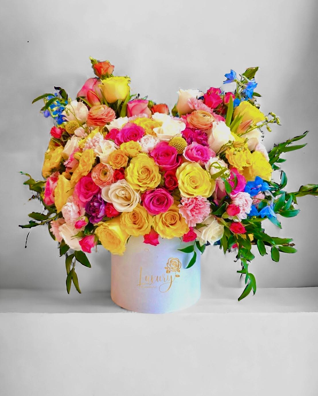 Andy  - “PLACE YOUR ORDER AT LEAST 2 DAYS PRIOR TO THE DELIVERY DATE”  This incredible arrangement, with a beautiful floral mix that includes Colombian roses, spray roses, delphinium, and a variety of seasonal foliage, is sure to be the centerpiece of your next event or special occasion.   6” White Cylinder Container  All Occasion Check our coverage area.  Occasionally, flowers and/or container substitutions happen due to weather, seasonality, and market conditions, which may affect availability. If this is the case with the gift you’ve selected, we will ensure that your arrangement's style, theme, and color scheme are preserved and will only substitute items of equal value or higher value.  CARE INSTRUCTIONS Gently mist the arrangement with natural water every other day. Do not spray any cleaning product on the flower arrangement. Do not place heavy objects directly on the flower arrangement. Keep them out of direct sunlight and extreme heat.