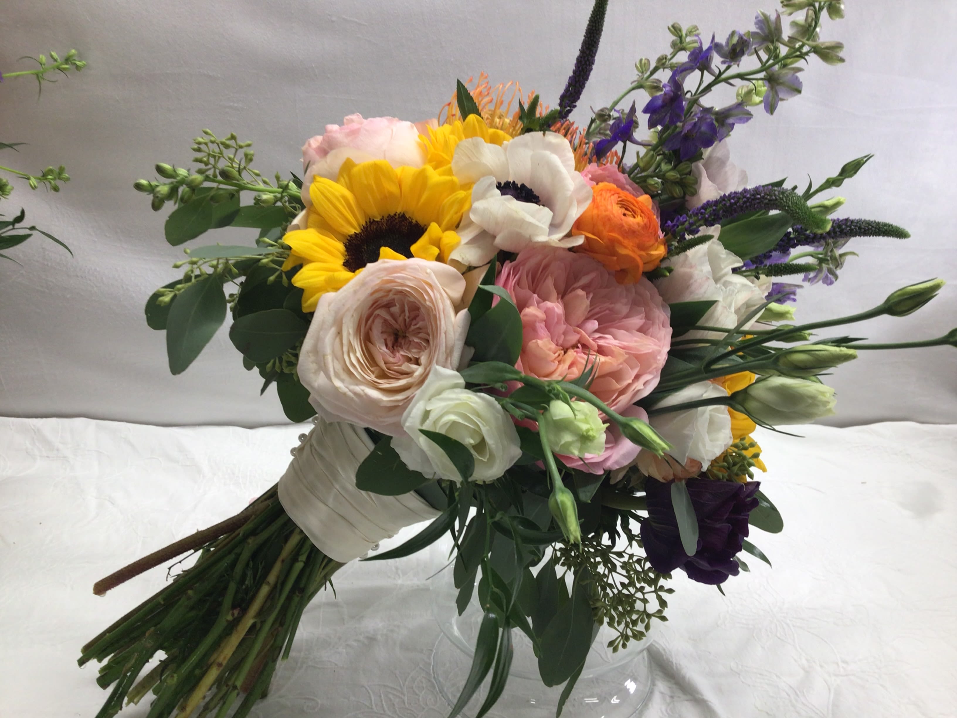 THE VICTORIA BOUQUET - This hand tied bouquet is suitable for any season or special occasion. Roses, sunflowers, anemone,  along with ranunculus and other garden flowers complete this timeless look. All special occasion bouquets can be modified with color and flower preferences to match your own personal, unique preferences. 